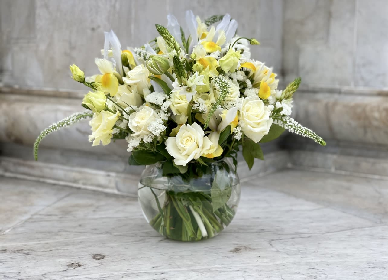 White and yellow floral arrangement in a round glass vase
