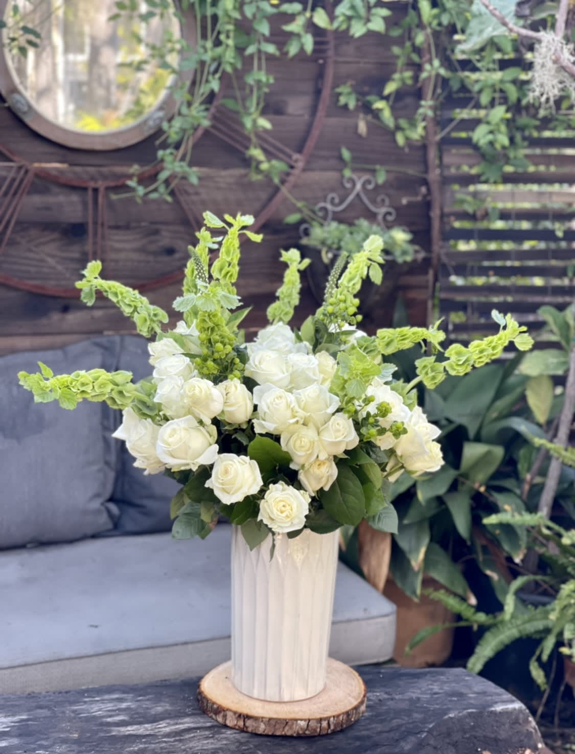 White roses and green spikes arranged in a tall vase