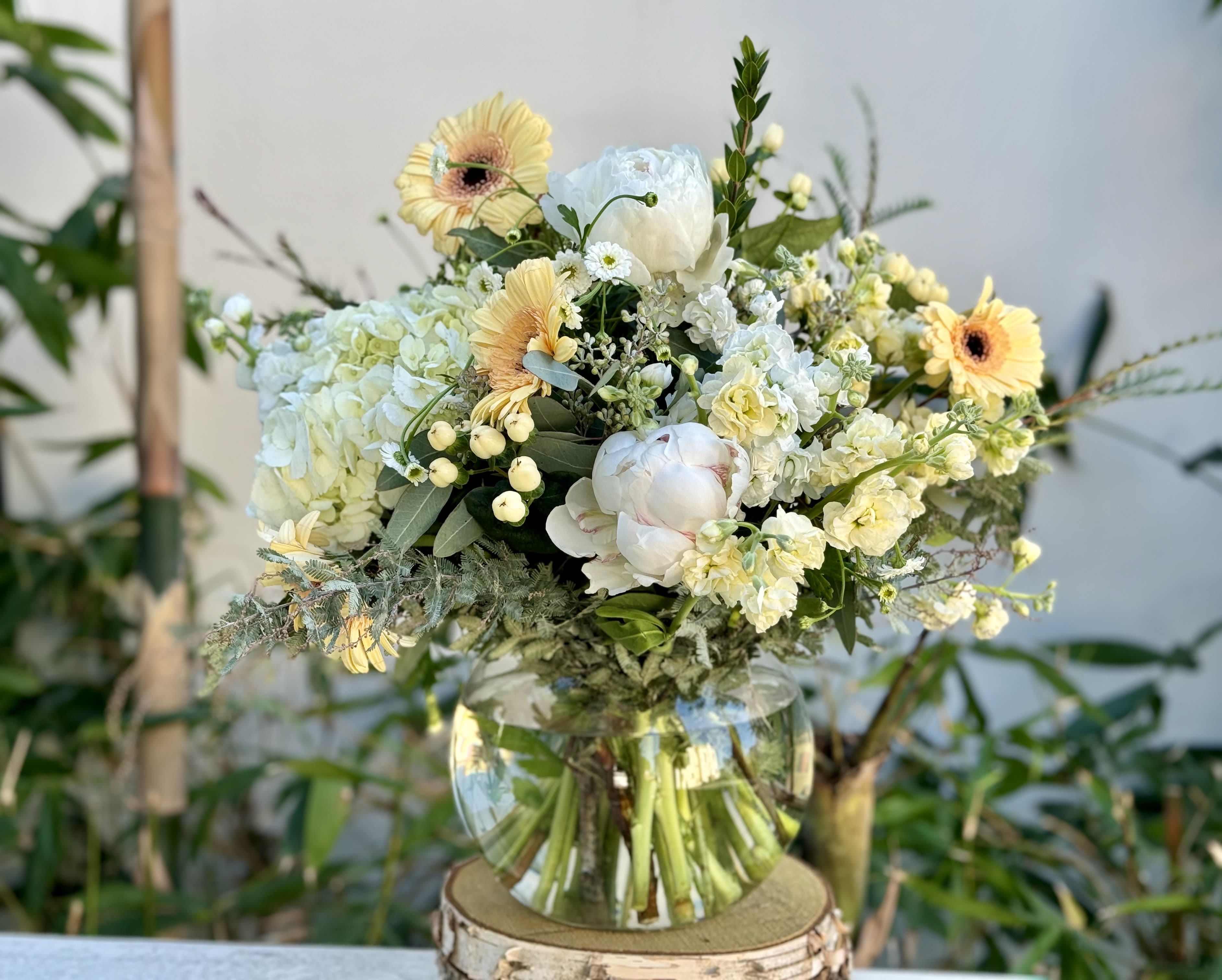 Mixed bouquet of pale yellow and white flowers in a clear glass vase