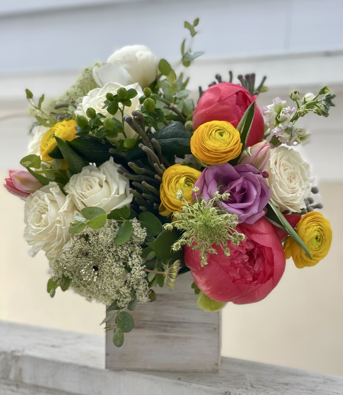 Colorful bouquet of roses and ranunculus in a wooden box