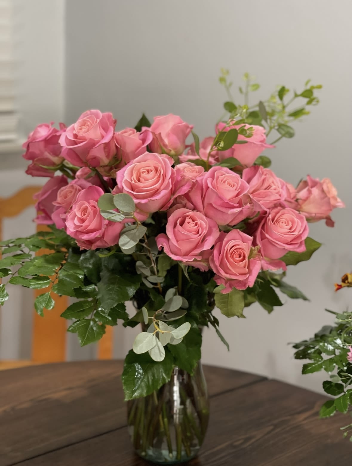 Pink roses arranged in a clear glass vase with greenery