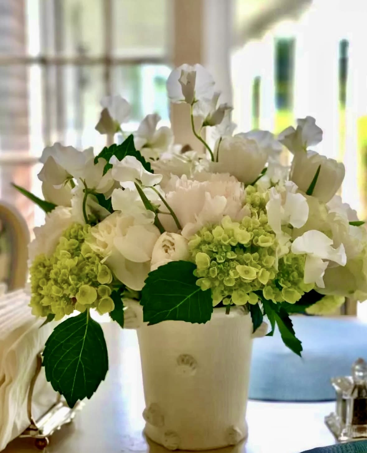 White flowers and pale green hydrangeas in a cream vase