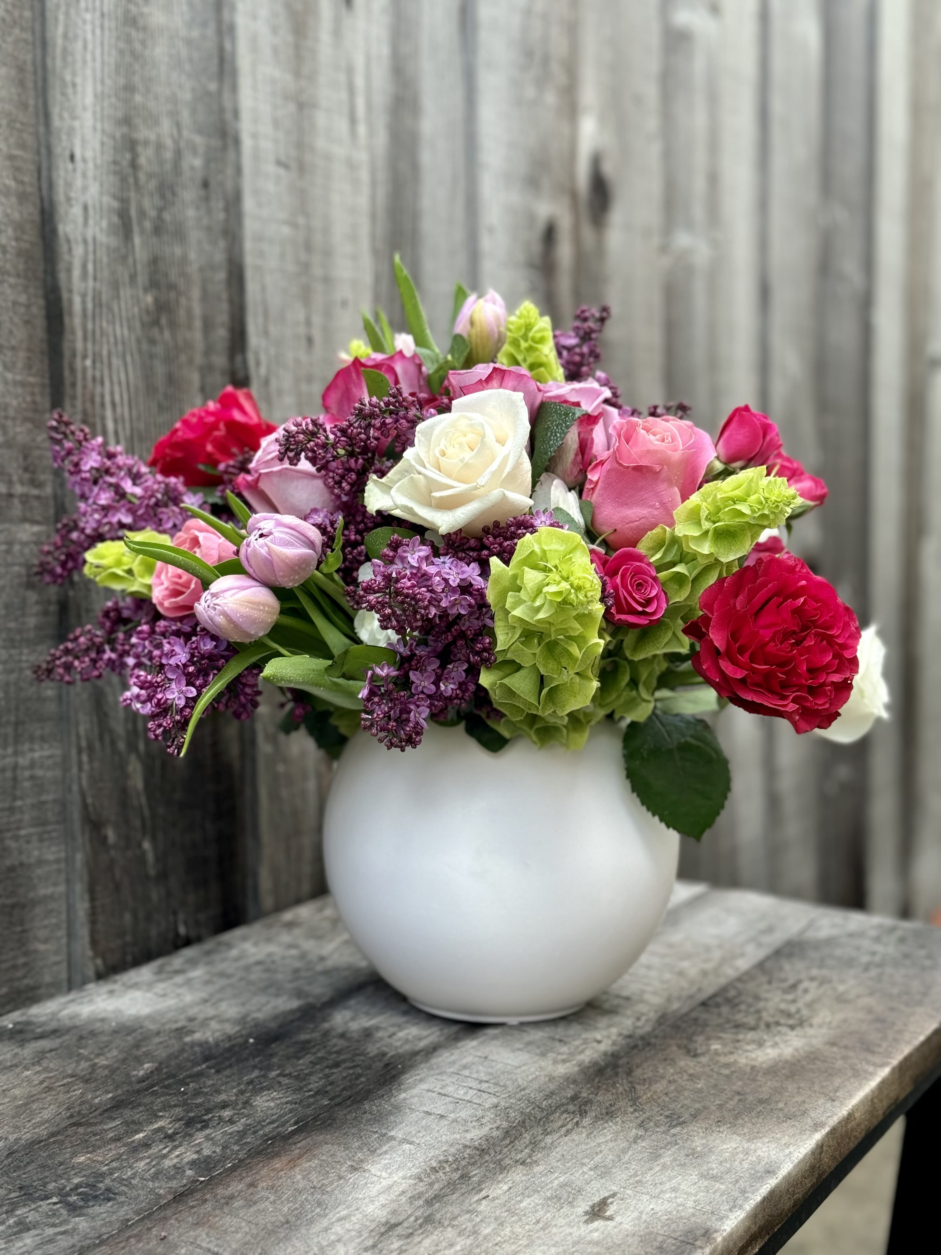 Mixed pink, white, and purple flowers in a white vase