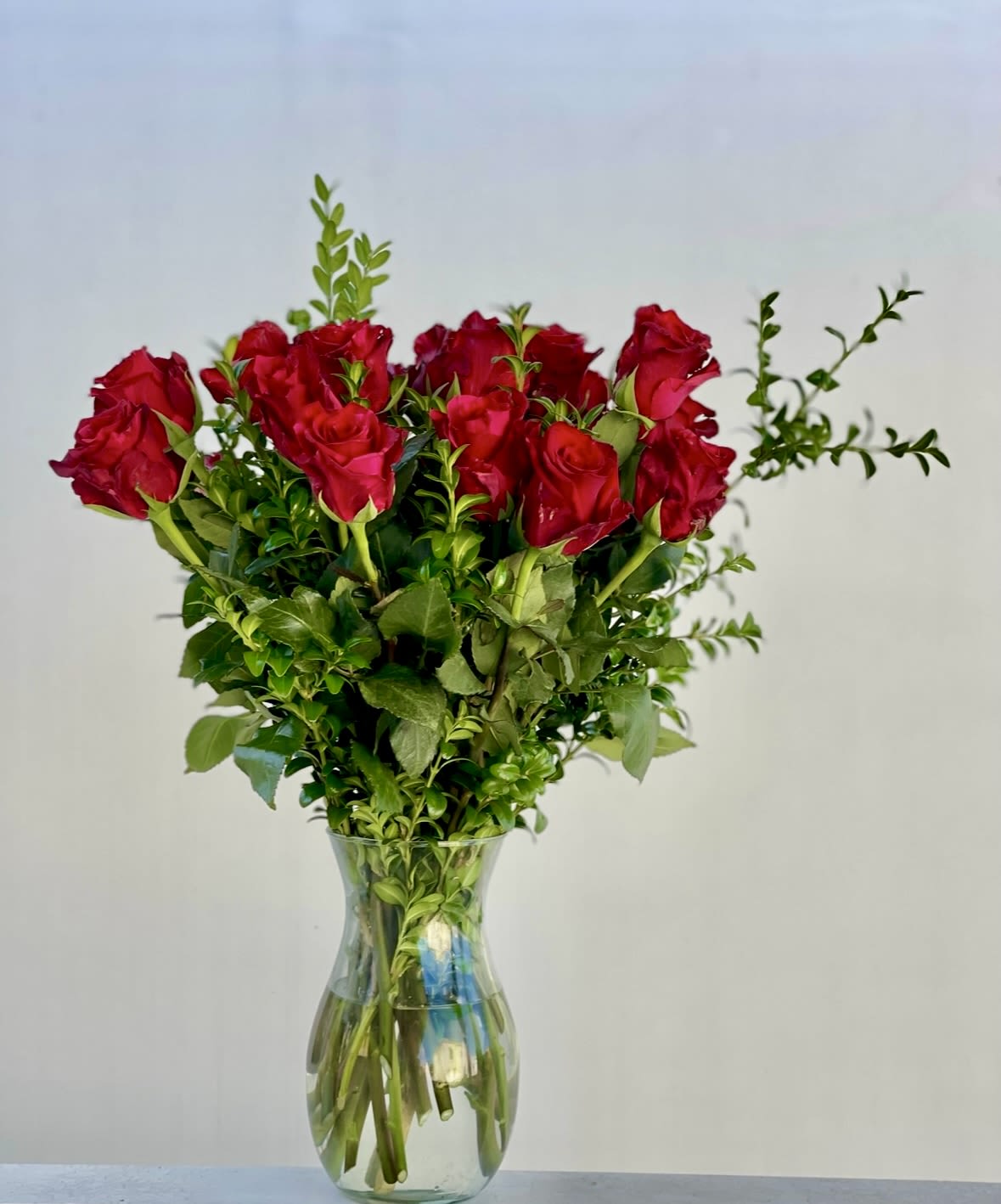 Red roses arranged in a clear glass vase
