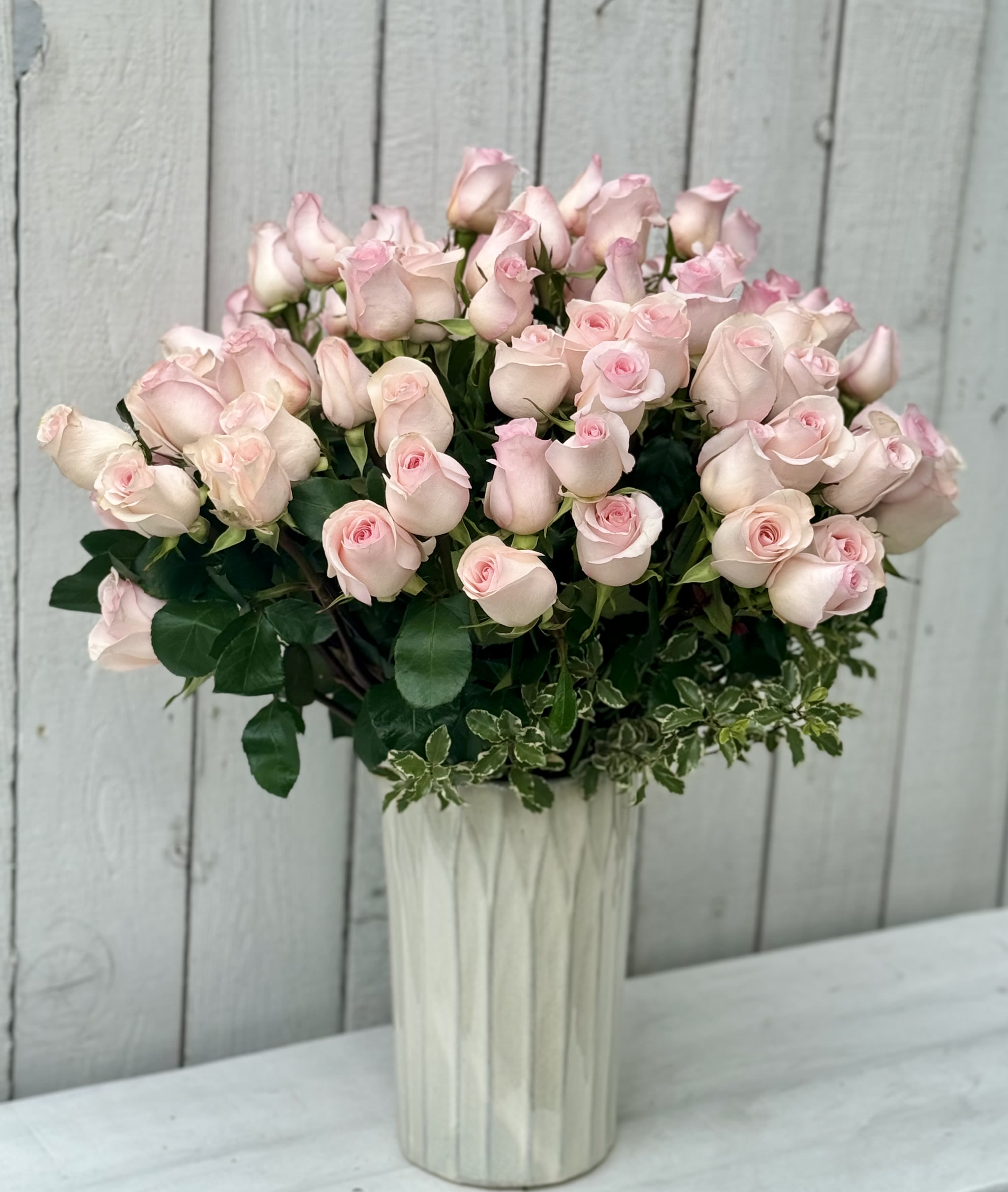 Bouquet of pale pink roses in a tall white vase