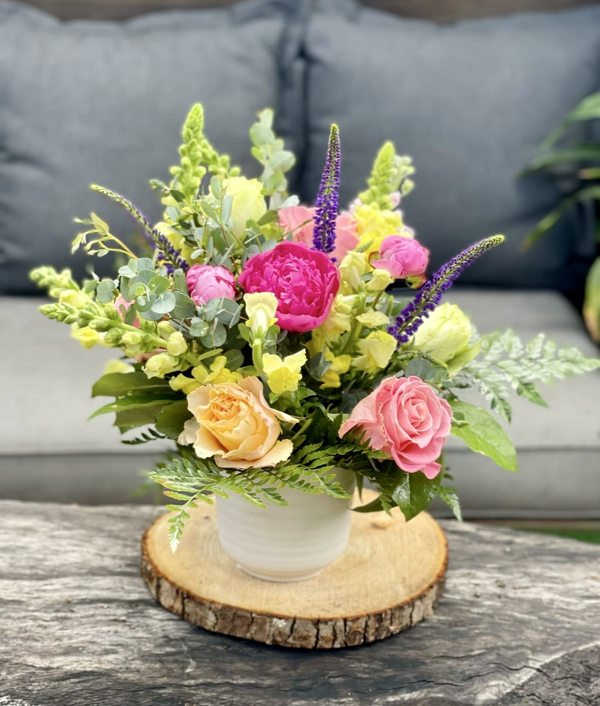 Mixed pink, yellow, and purple flowers in a white pot