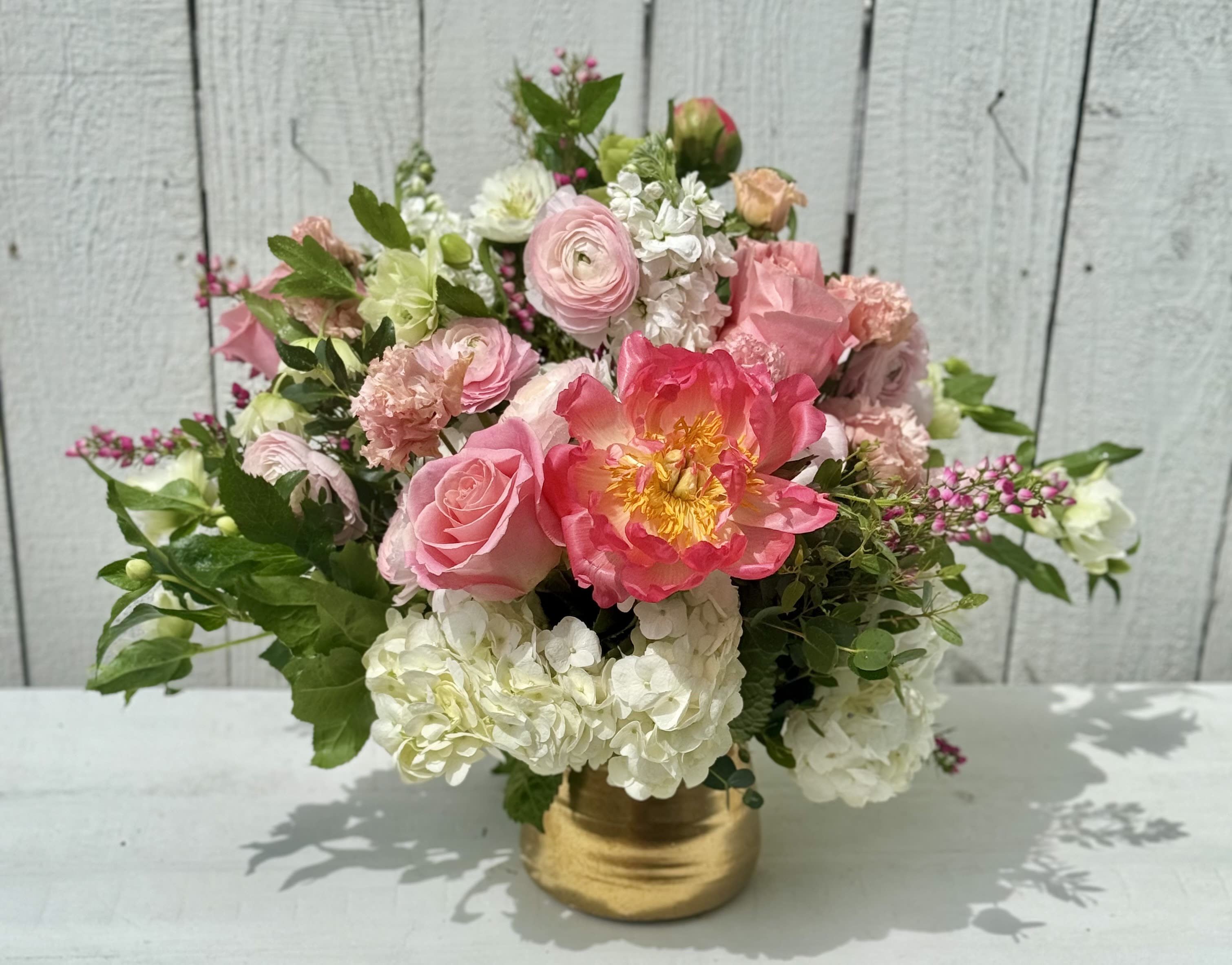 SMALL TOWN CHARM - A stunning arrangement for those who love pink! This beauty has peonies, ranunculous, lisianthus, heloboris, gorgeous in season pink berries and fluffy white hydrangeas. It comes designed in a beautiful 6x8 gold container.