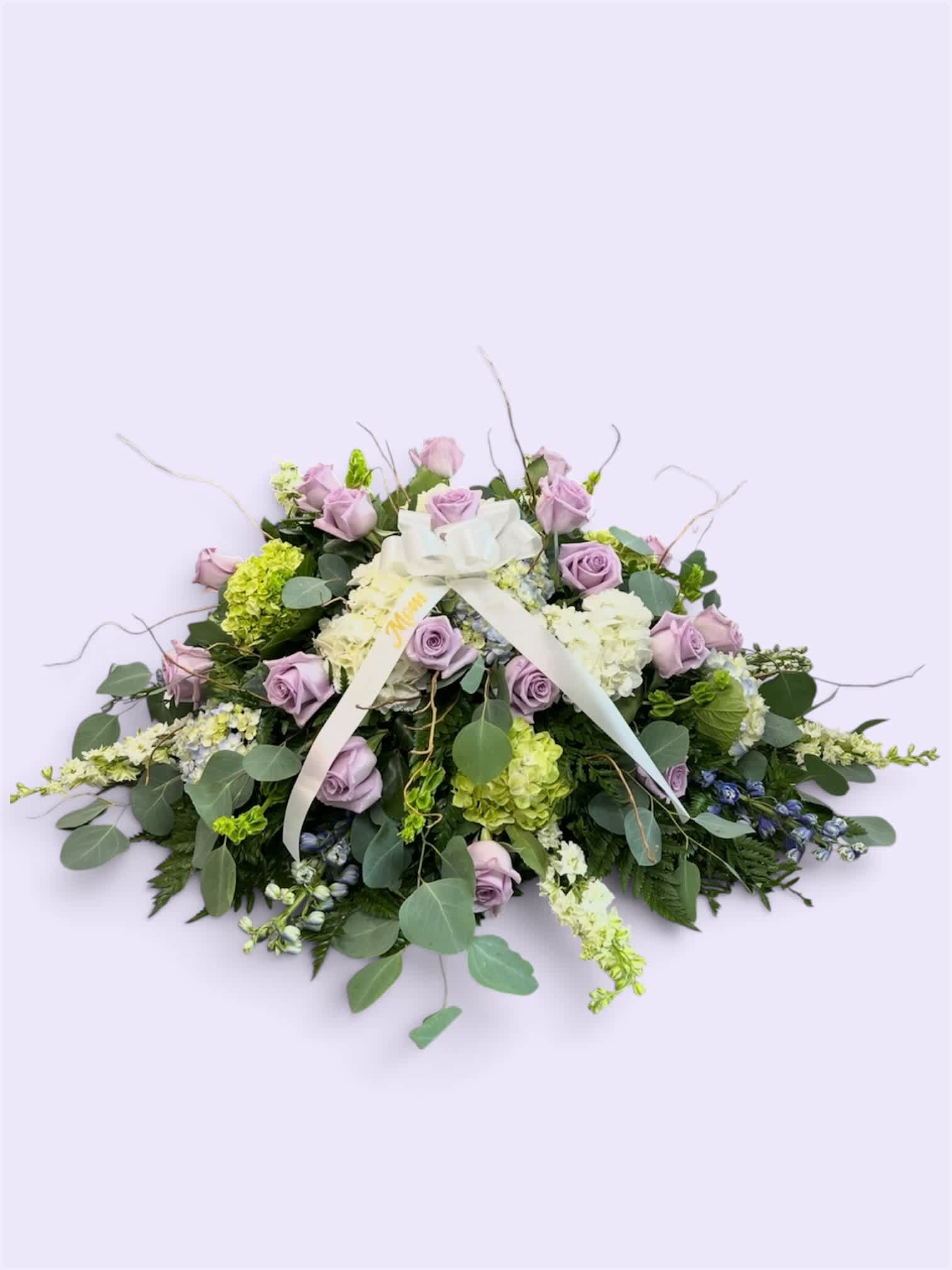 Lavender roses and white hydrangeas in a low floral arrangement with a ribbon bow