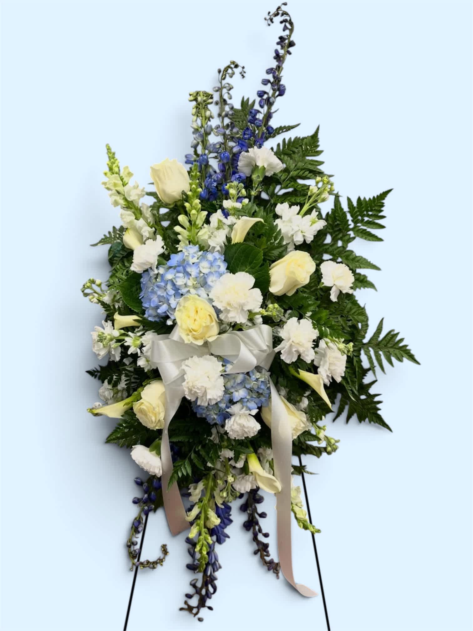 Standing floral spray with white roses, blue hydrangea, and ribbon
