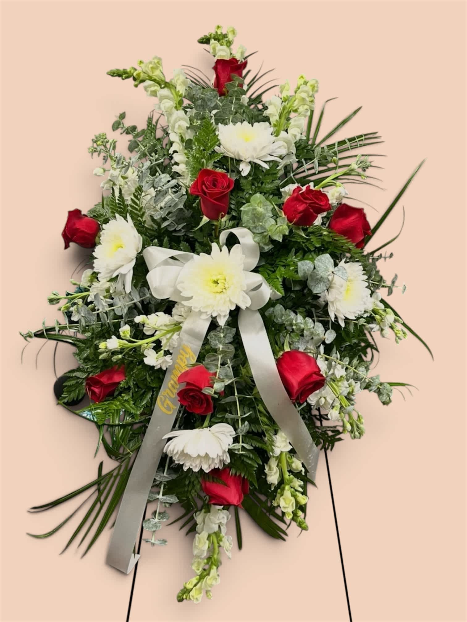 Standing floral spray with red roses and white daisies on a ribboned easel