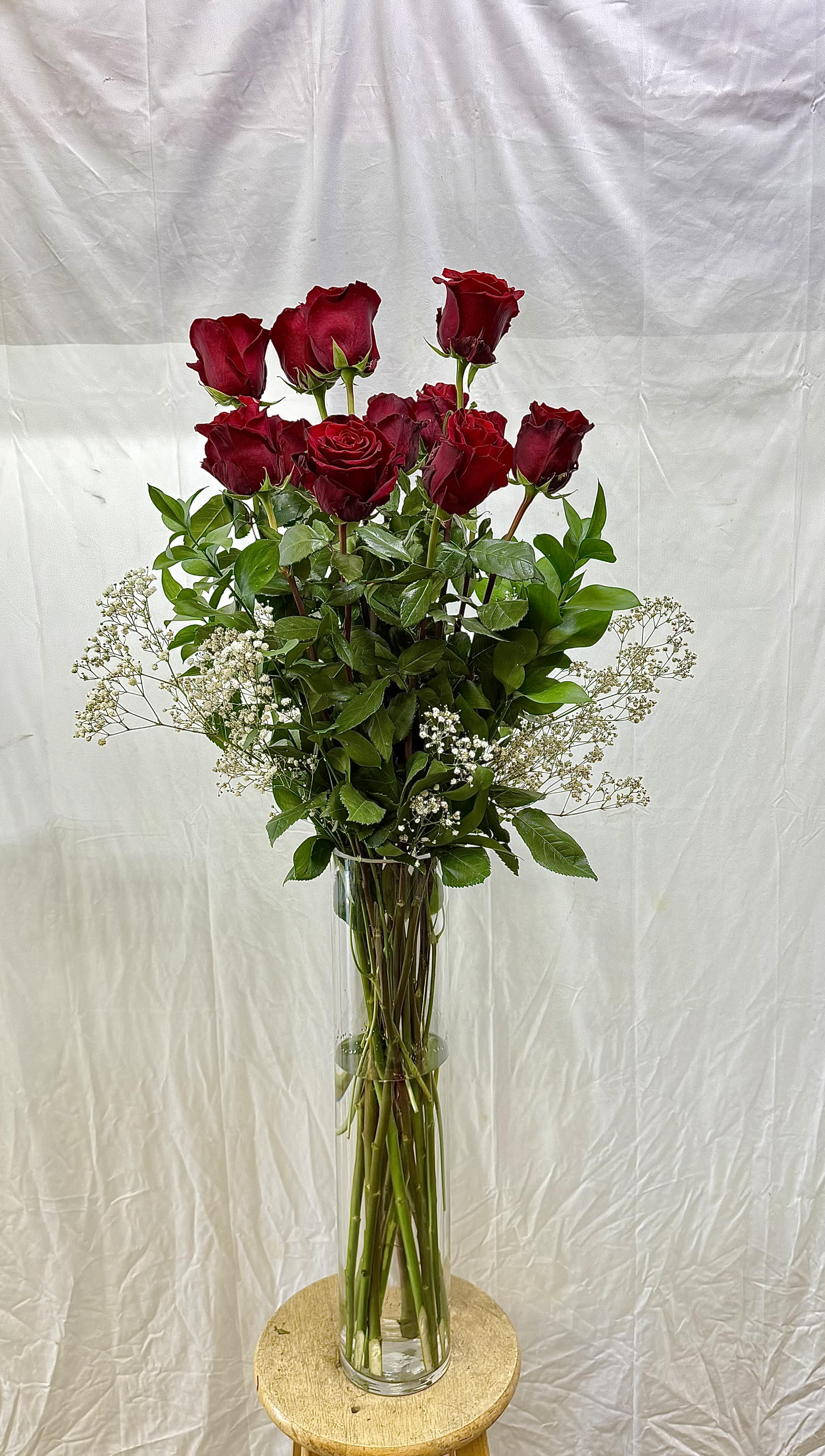 Tall vase arrangement of red roses with white baby's breath