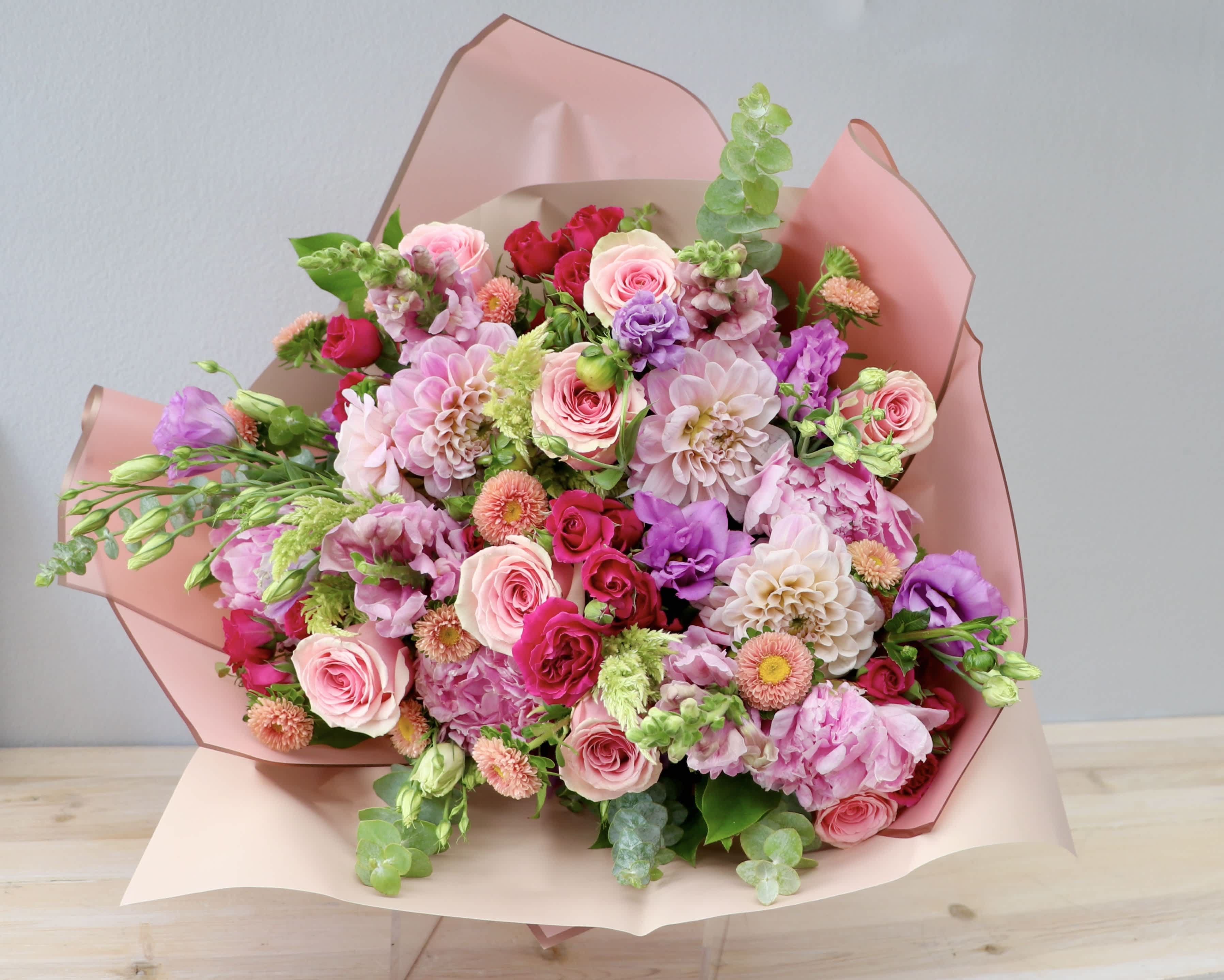 Rose and Amethyst Bouquet - Featuring a lush blend of blush dahlias, classic pink roses, magenta spray roses, delicate lavender lisianthus, and textured pink peonies all framed with fresh eucalyptus greens.