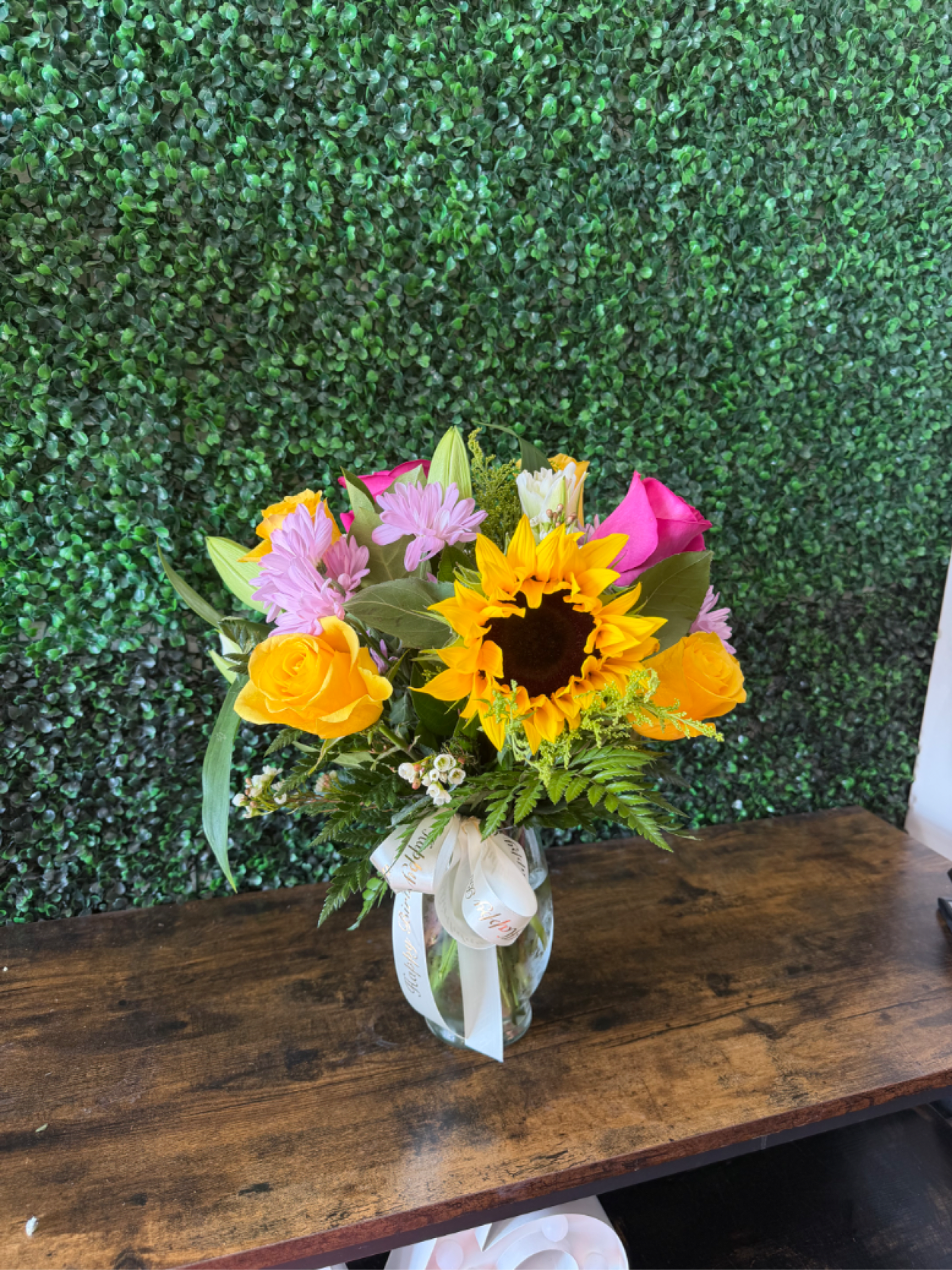 Blooming sunshine  - A beautiful burst of sunshine in a vase! this cheerful arrangement features vibrant, sunflowers, purple and pink roses, delicate lilies, bright daisies, golden solidago, and fresh greenery. Perfect for birthdays, celebrations,  thank-yous, congratulations or simply brightening someone’s day.