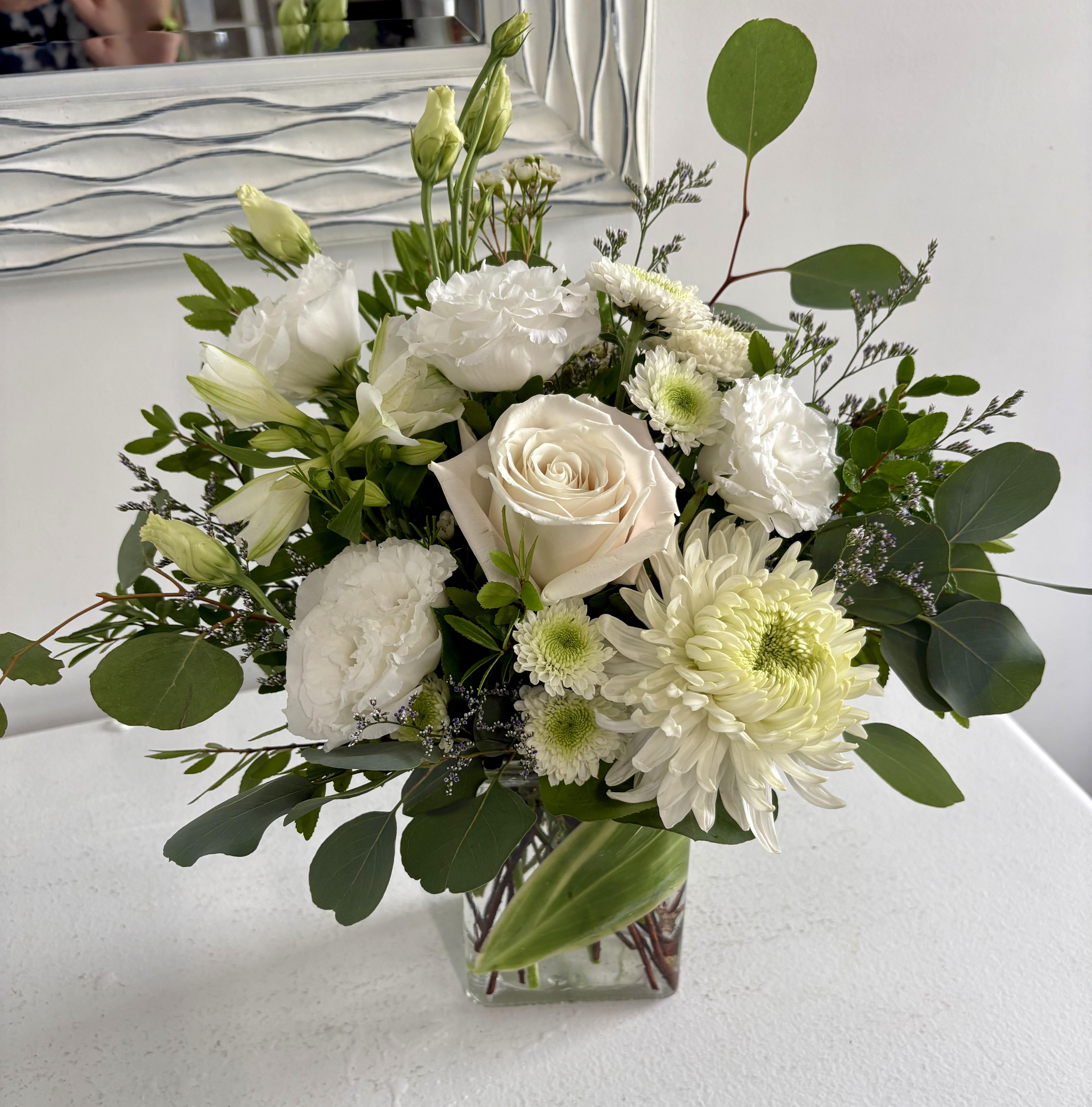 White floral bouquet in a clear square vase