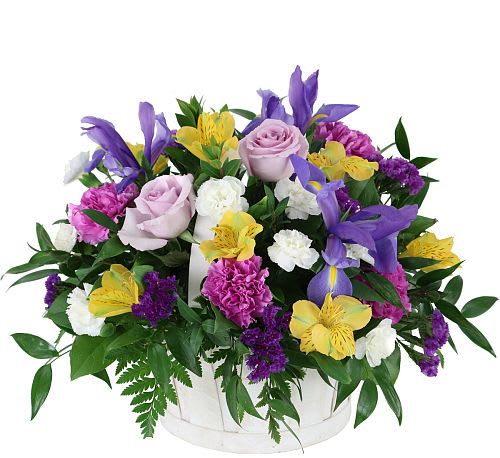Mixed bouquet of roses, lilies, and carnations in a white basket