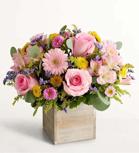 Pink roses and mixed flowers arranged in a wooden box