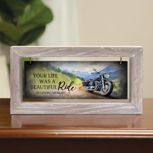 Memorial plaque in a light wood frame with a motorcycle scene