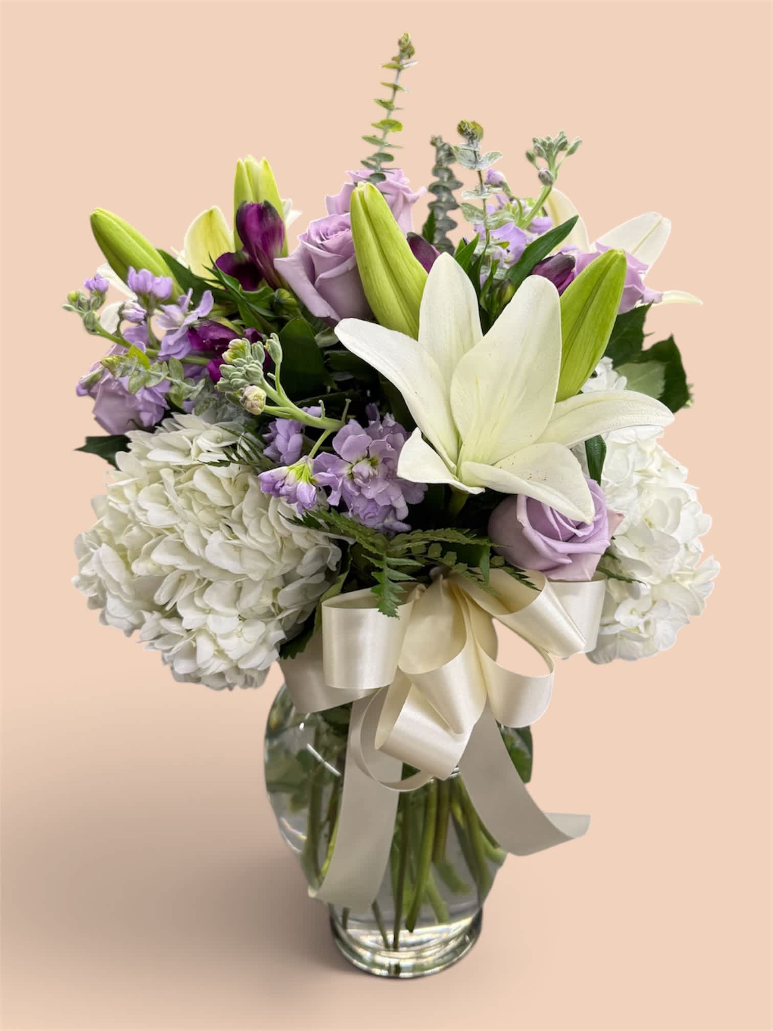 Lavender and white bouquet with lilies and roses in a glass vase