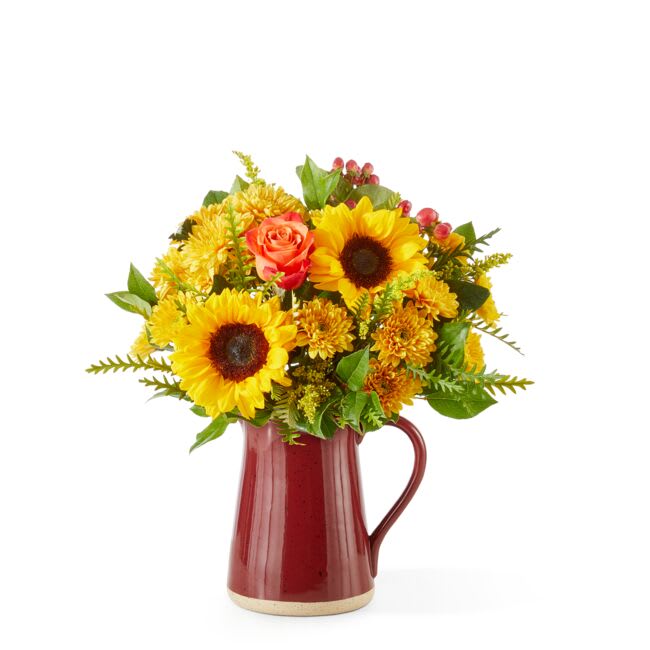 Sunflower and orange rose arrangement in a red pitcher vase
