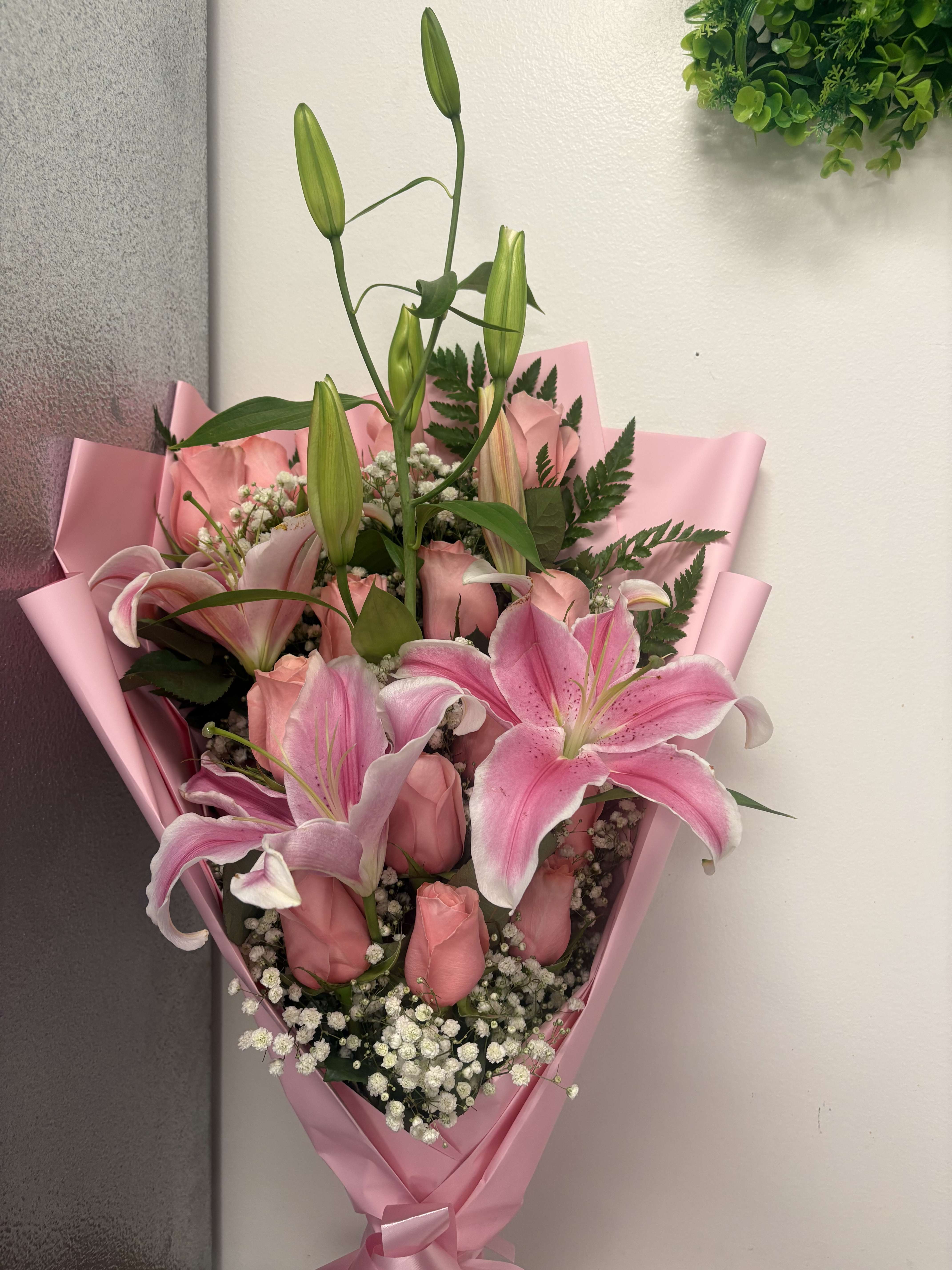 Pink lily and rose bouquet wrapped in pink paper