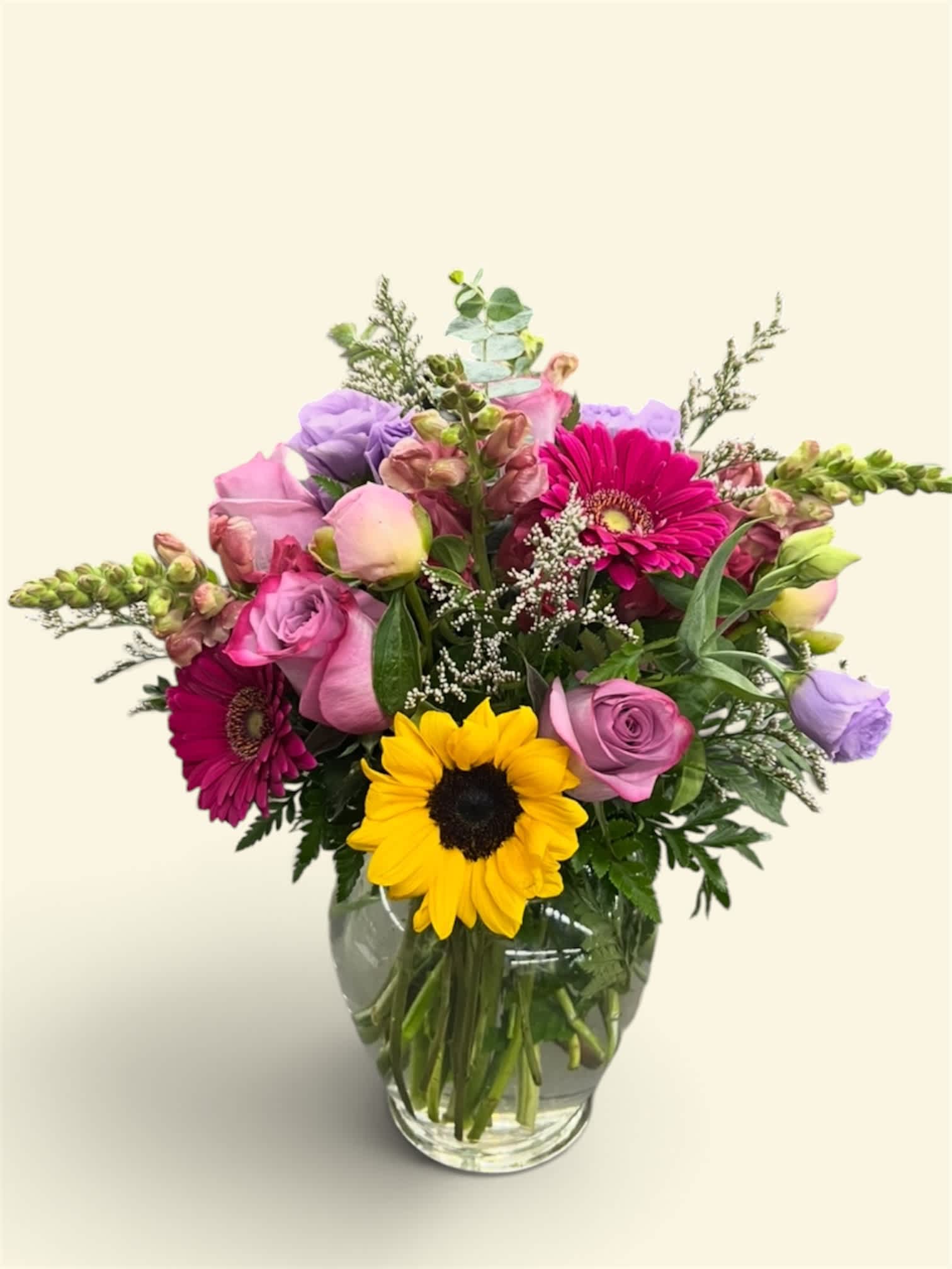 Mixed bouquet in a glass vase with sunflowers, roses, and pink gerberas