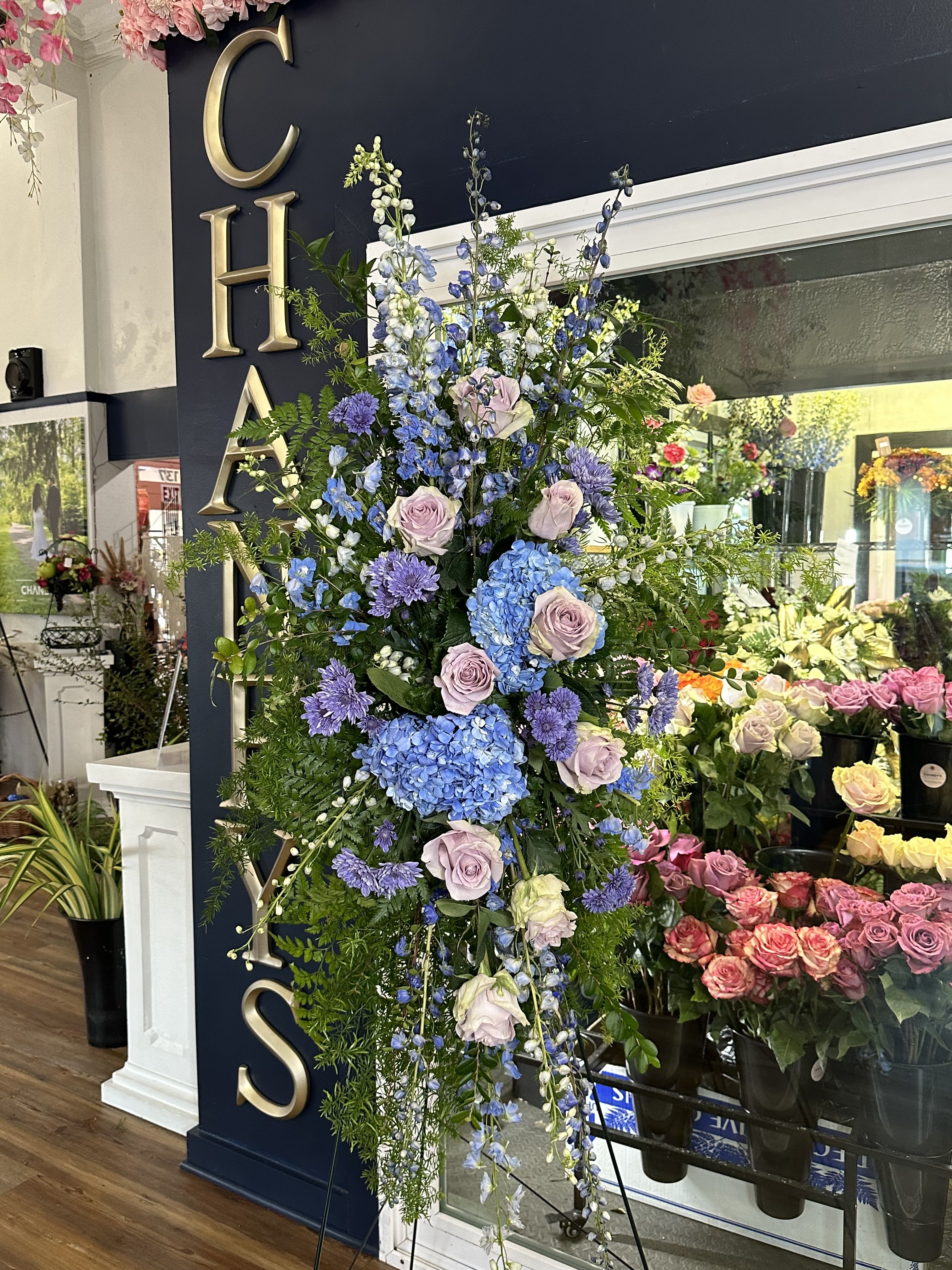 Tall floral standing spray with blue, lavender, and white blooms