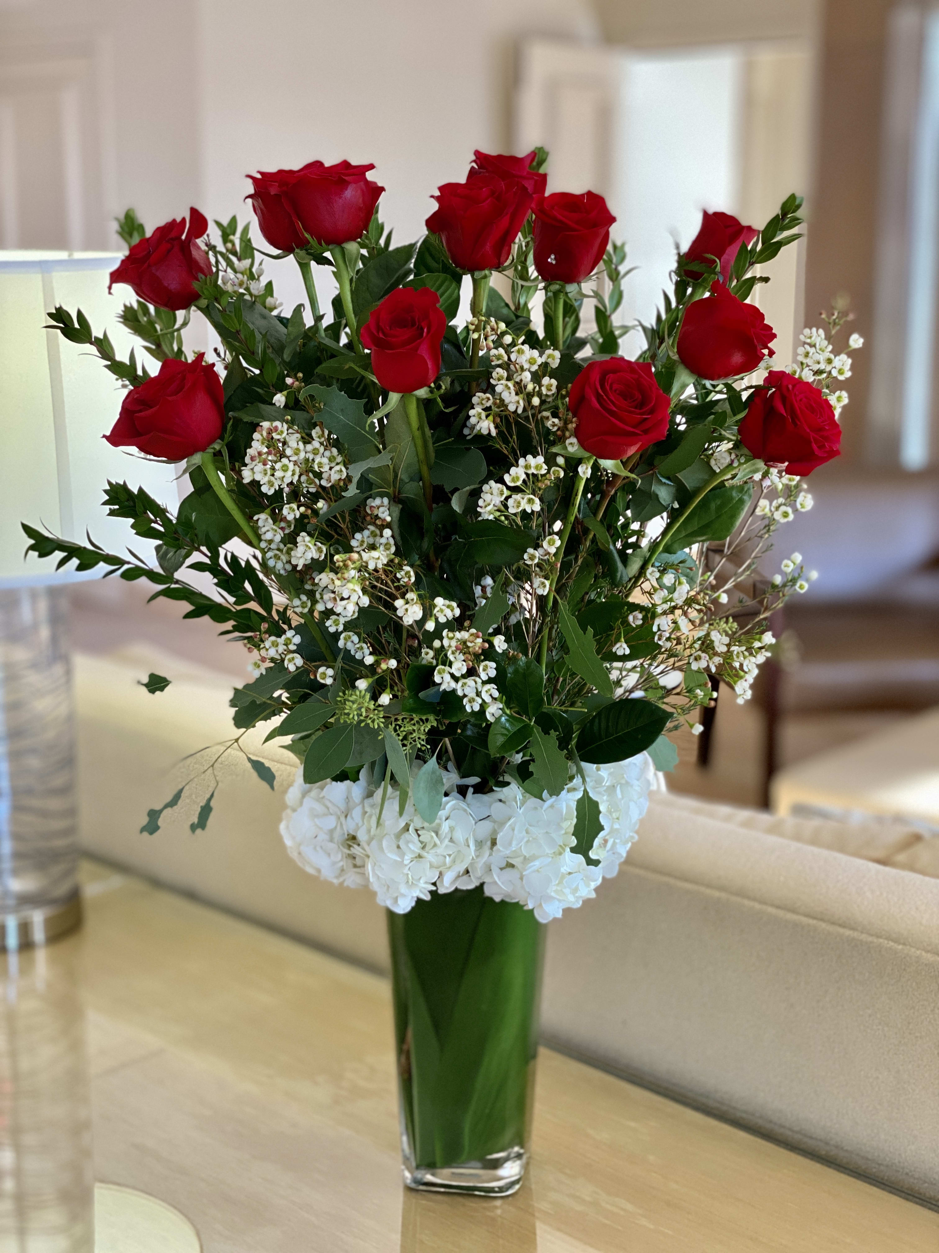 Red roses and white hydrangeas in a tall glass vase
