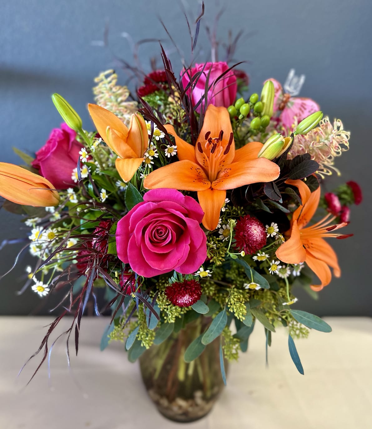 Bright bouquet of orange lilies and pink roses in a glass vase