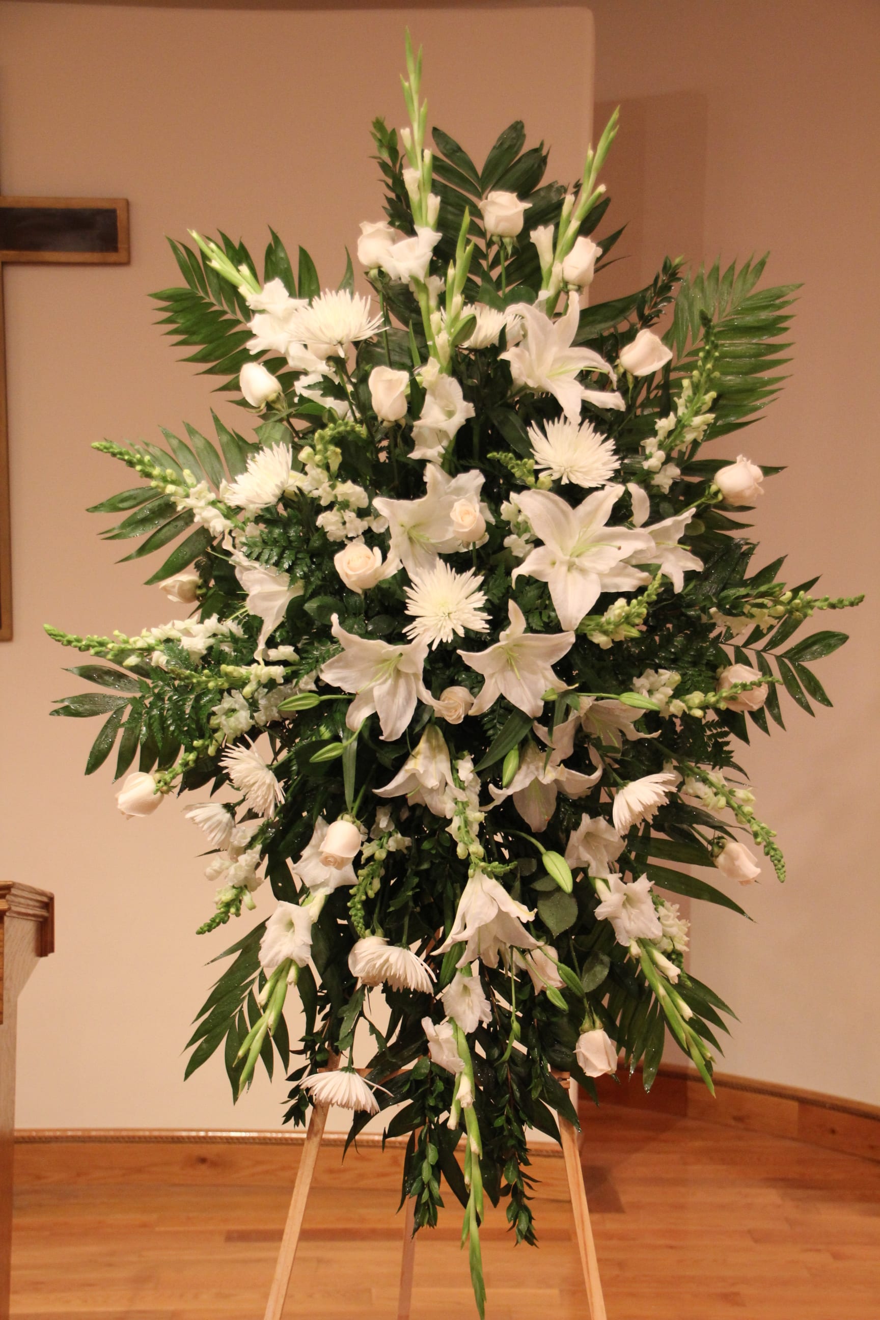 White funeral spray with lilies and roses on a standing easel