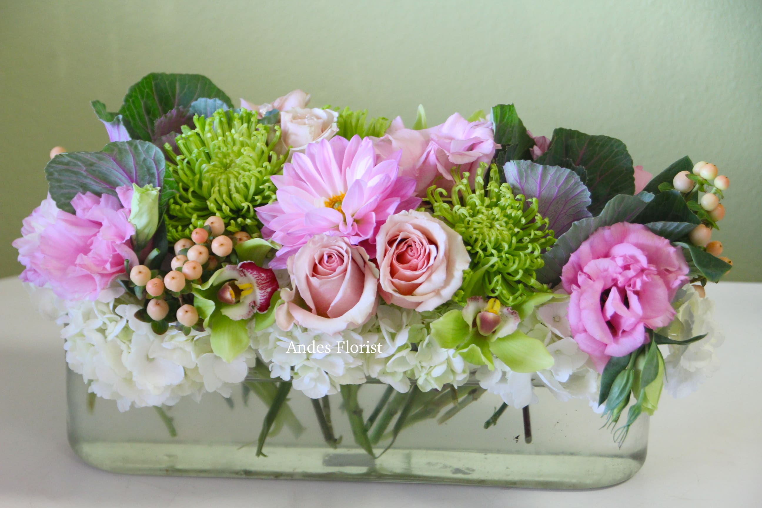 Pink and green floral arrangement in a clear rectangular vase