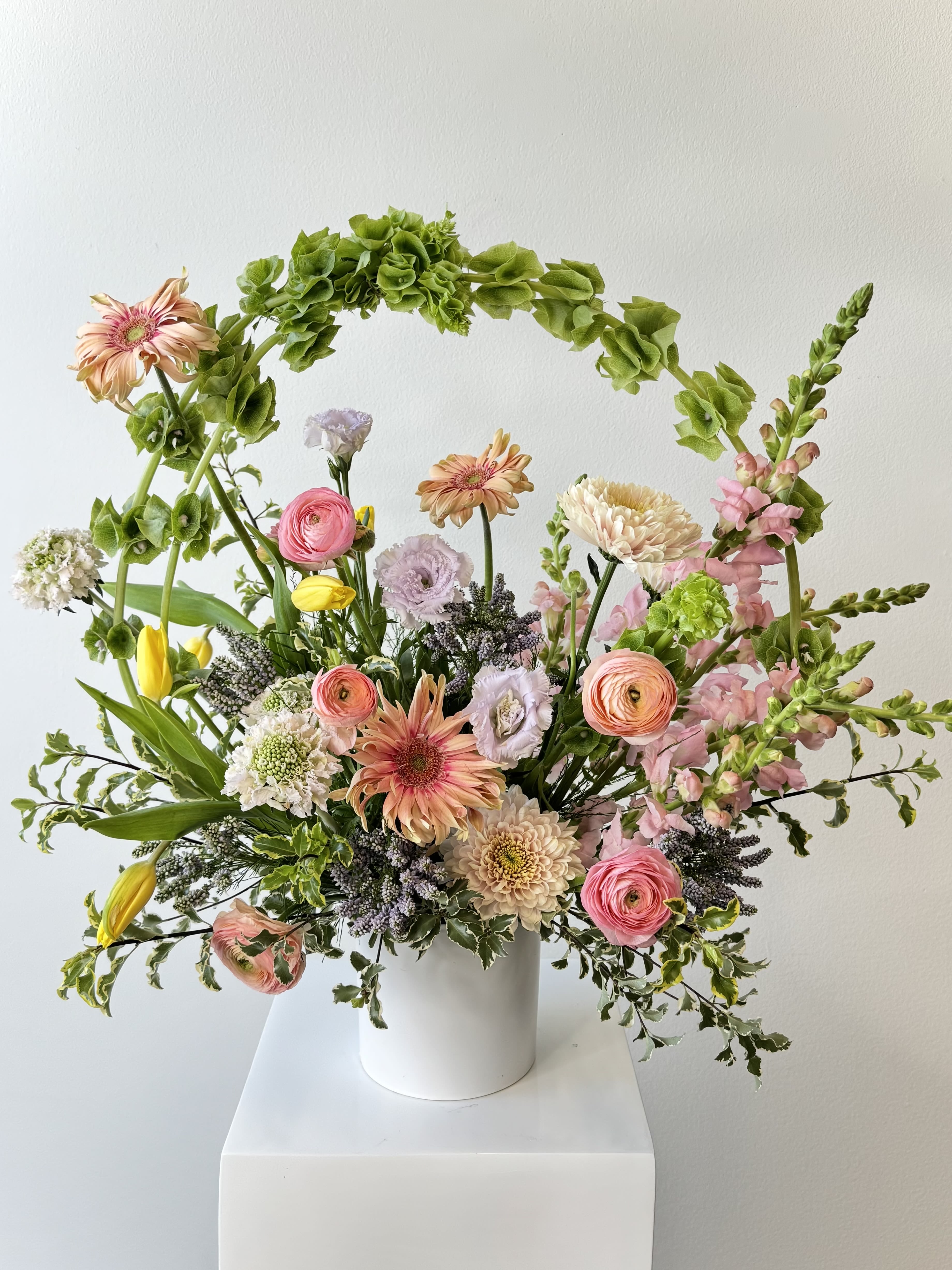 Mixed pastel bouquet in a white vase with pink, peach, and yellow blooms
