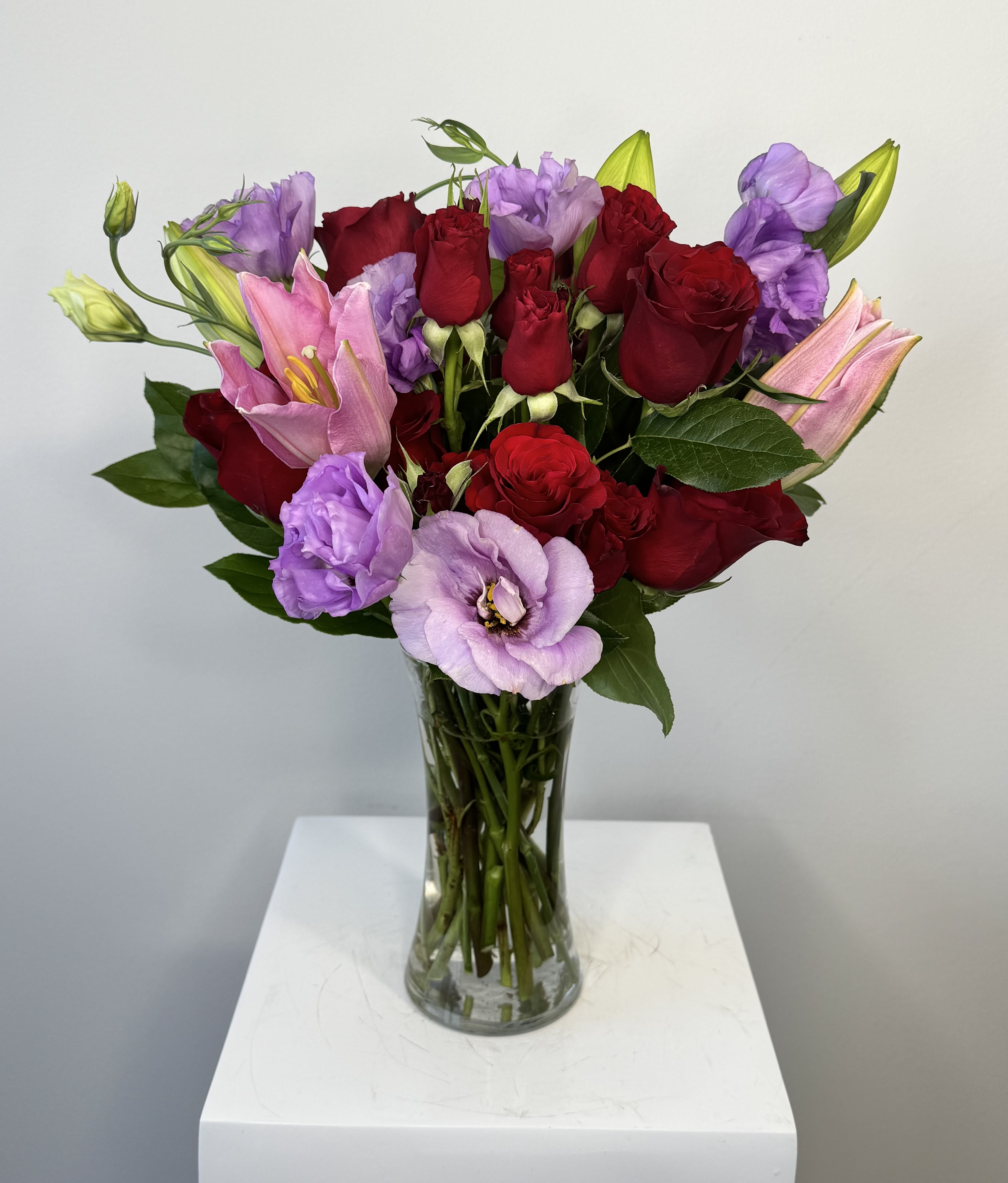 Bouquet of red roses and pink lilies in a clear glass vase