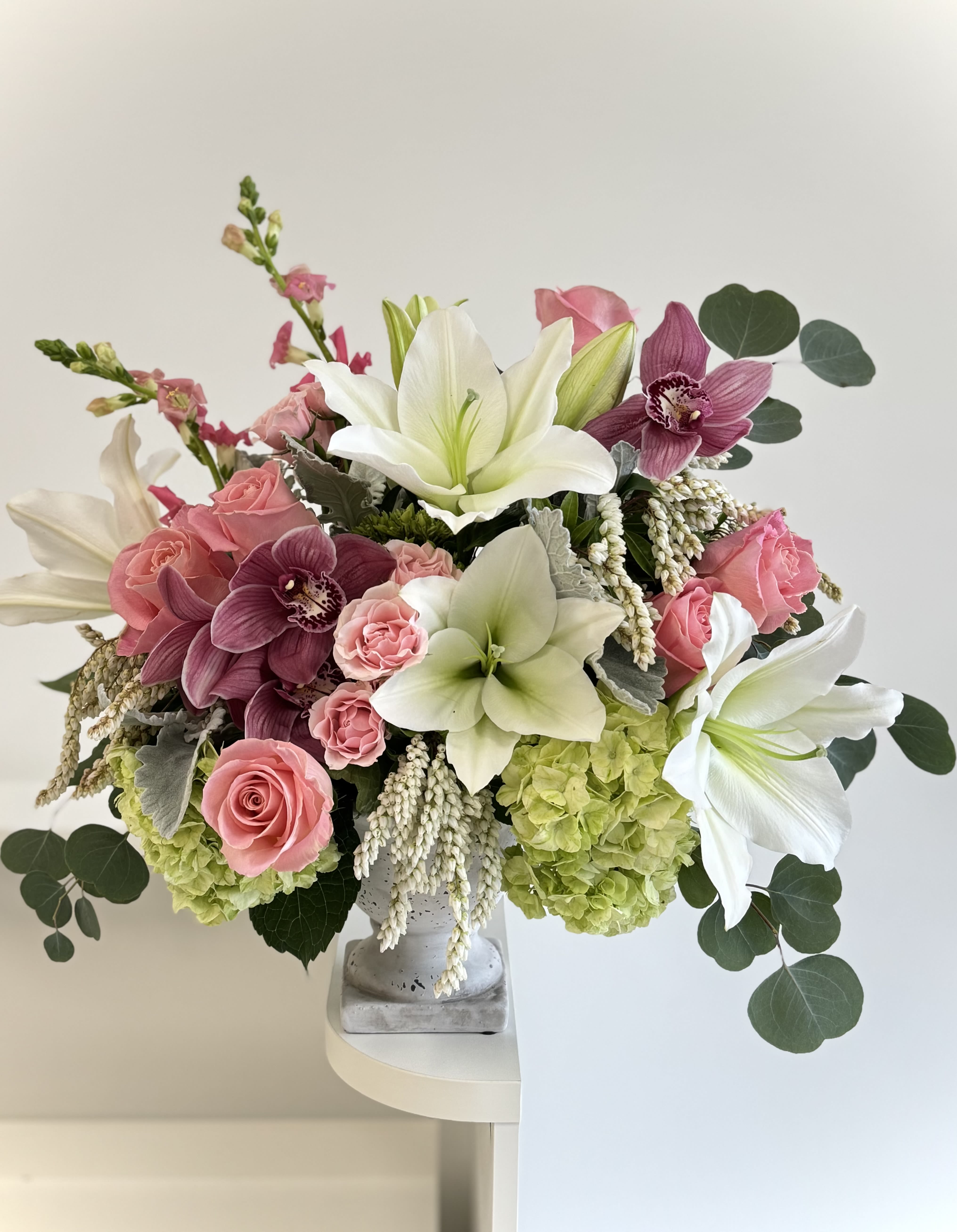 Pink roses and white lilies arranged in a gray vase