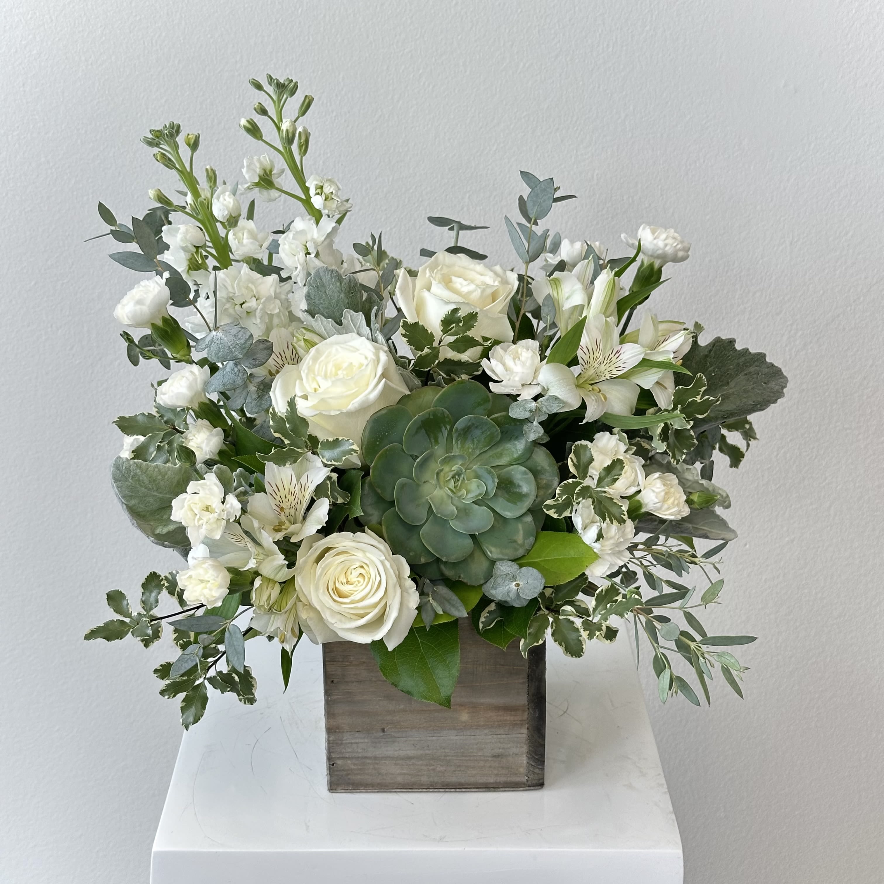 White roses and mixed white flowers in a wooden box with a succulent centerpiece