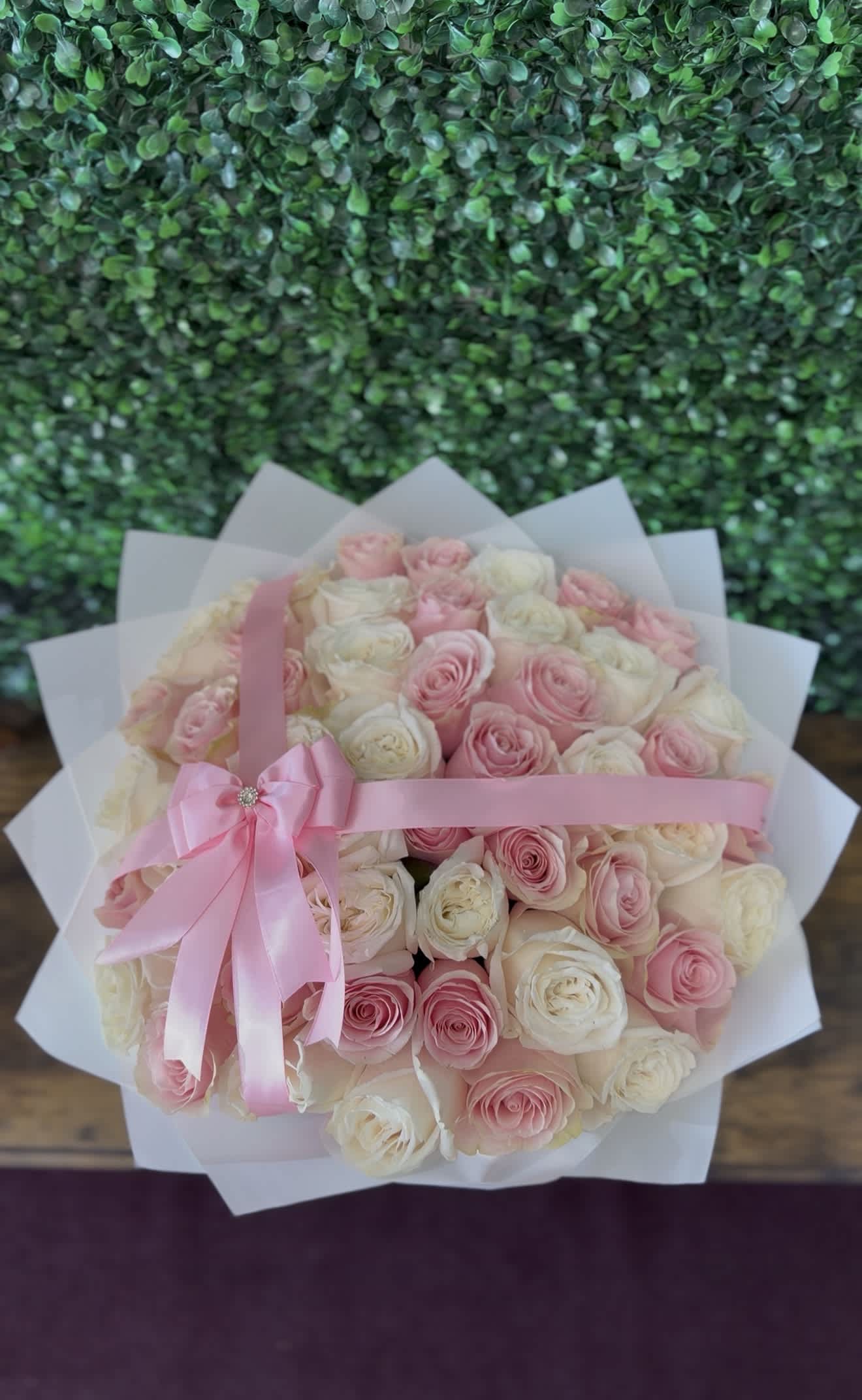 Bouquet of pink and white roses wrapped in white paper with a pink ribbon
