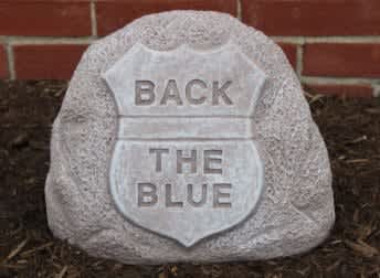 A stone sign shaped like a police badge with the words "BACK THE BLUE."