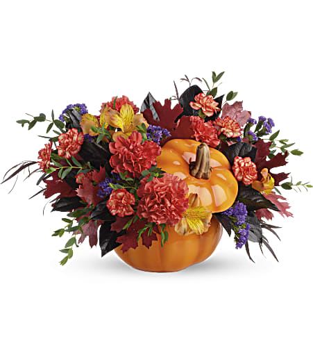 Pumpkin centerpiece with mixed fall flowers and leaves