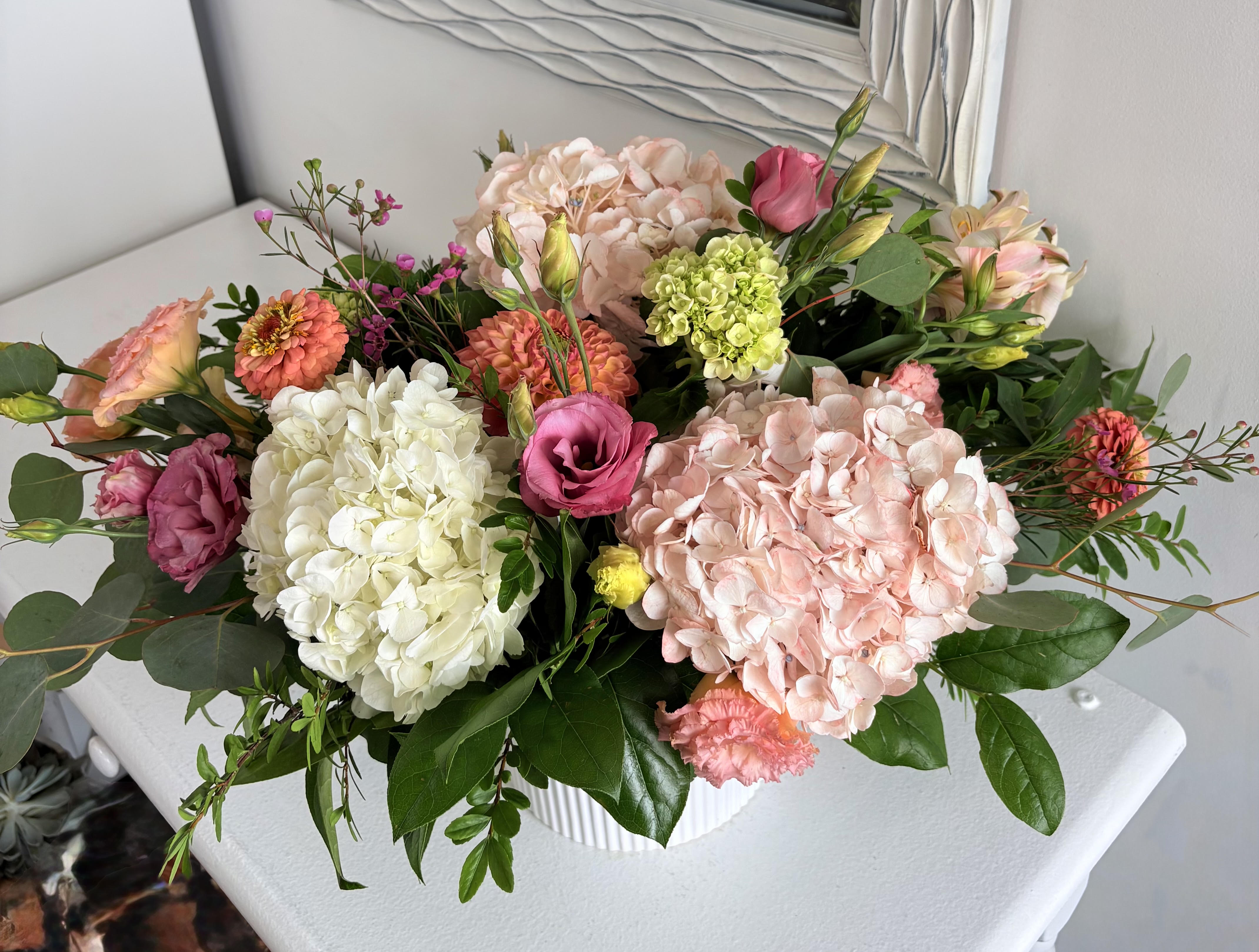 Mixed pink and white floral arrangement in a white vase