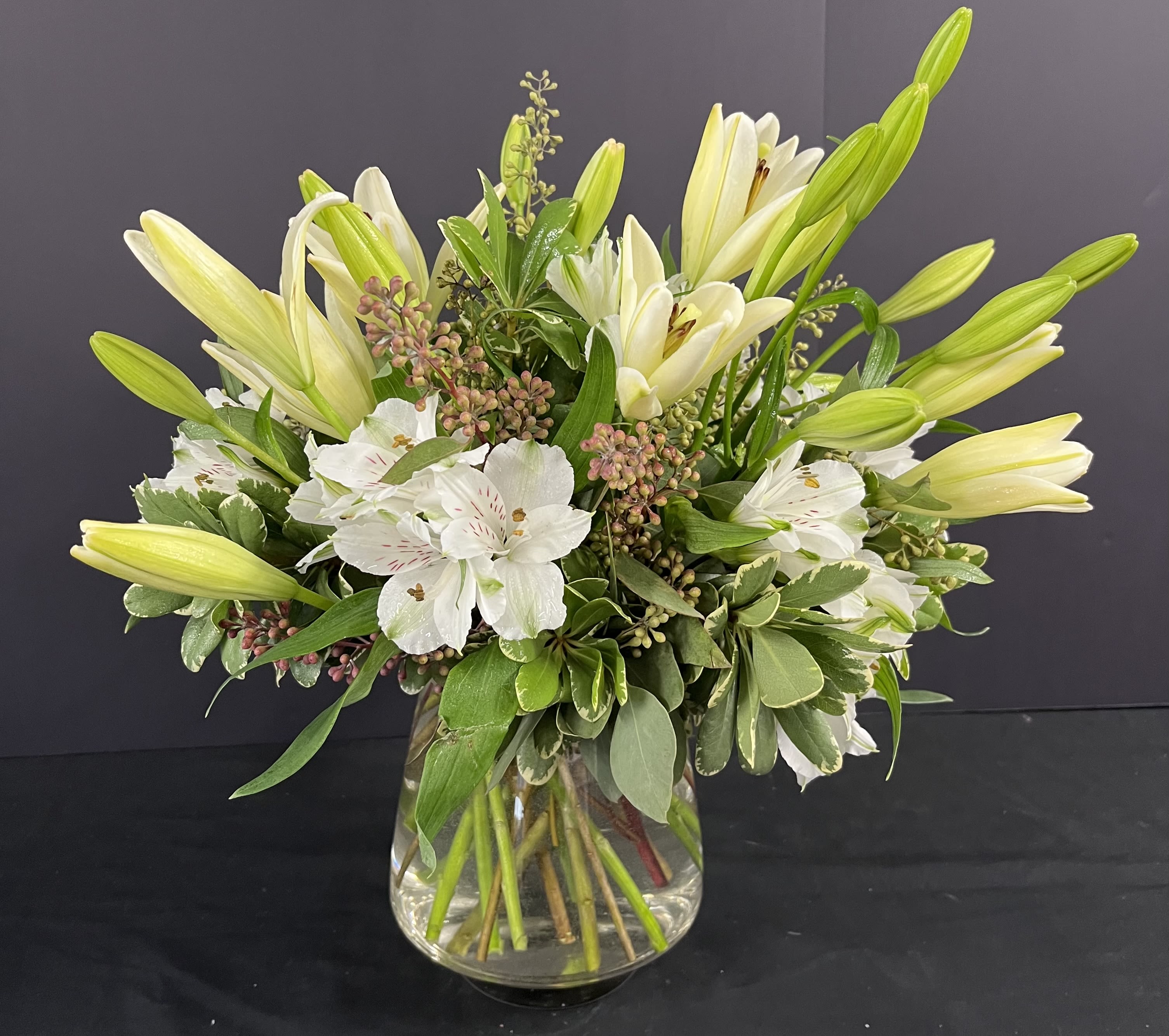 White lilies and alstroemeria in a clear glass vase