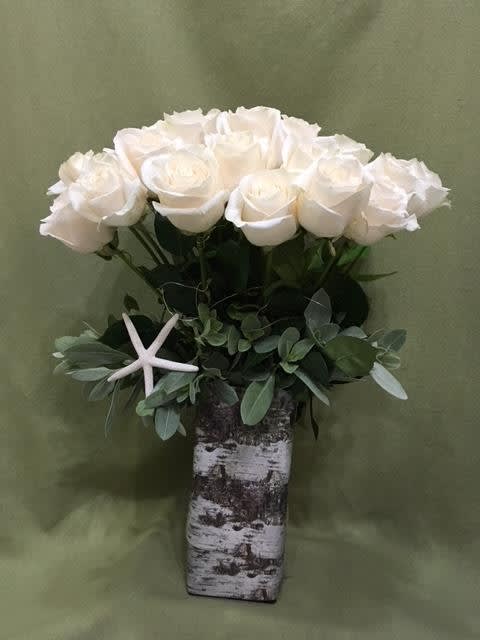 White roses in a birch vase with greenery and a starfish accent