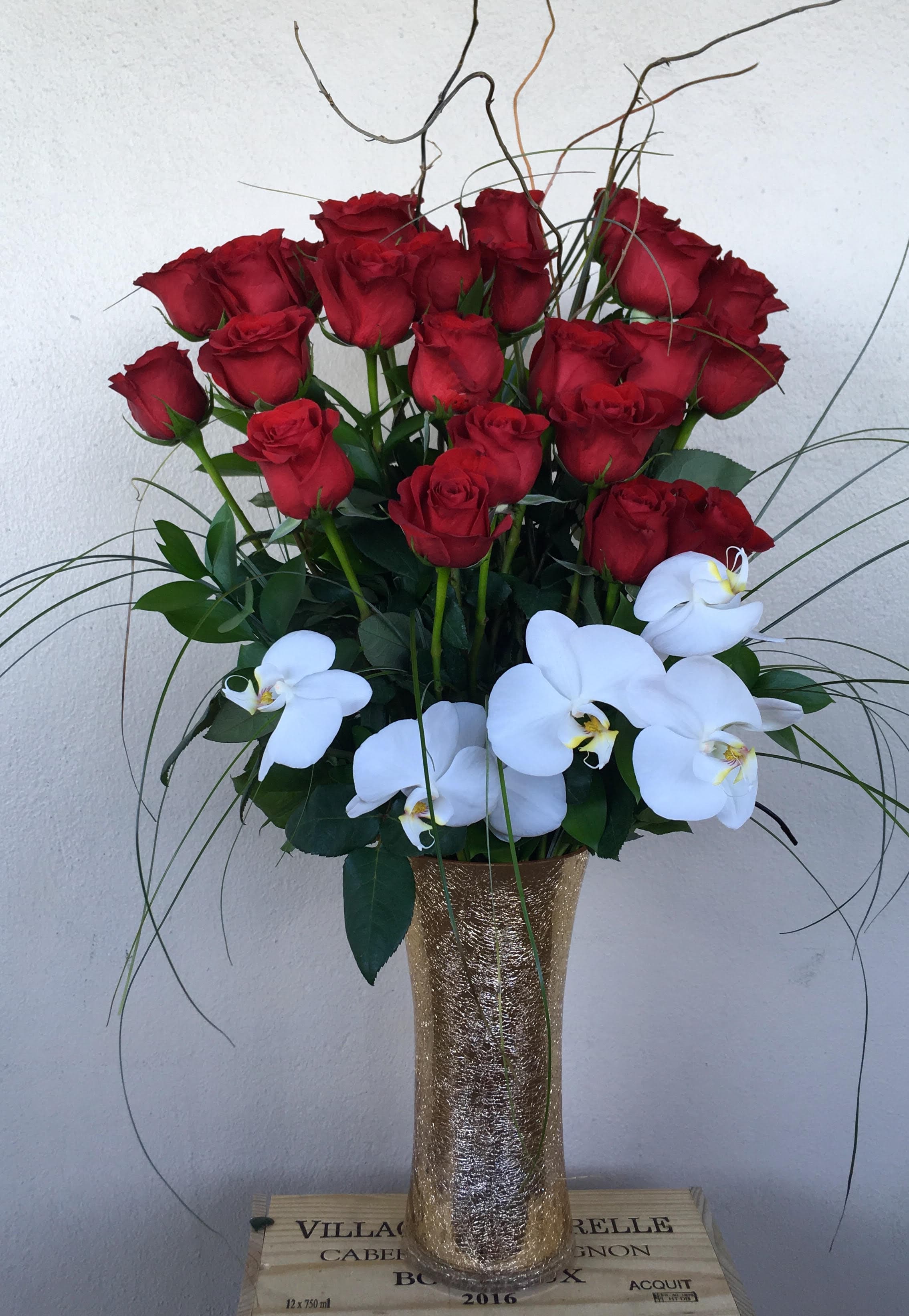 Red roses and white orchids arranged in a tall gold vase