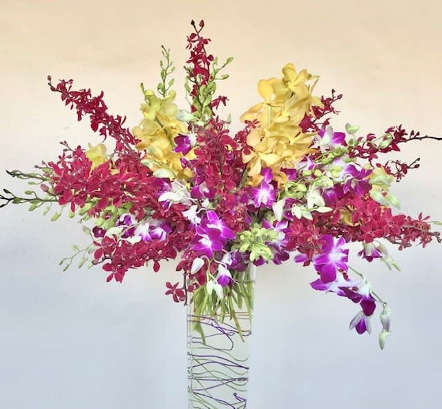 Colorful orchid arrangement in a tall clear glass vase