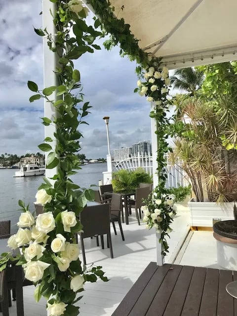 White rose floral arch on a waterfront patio
