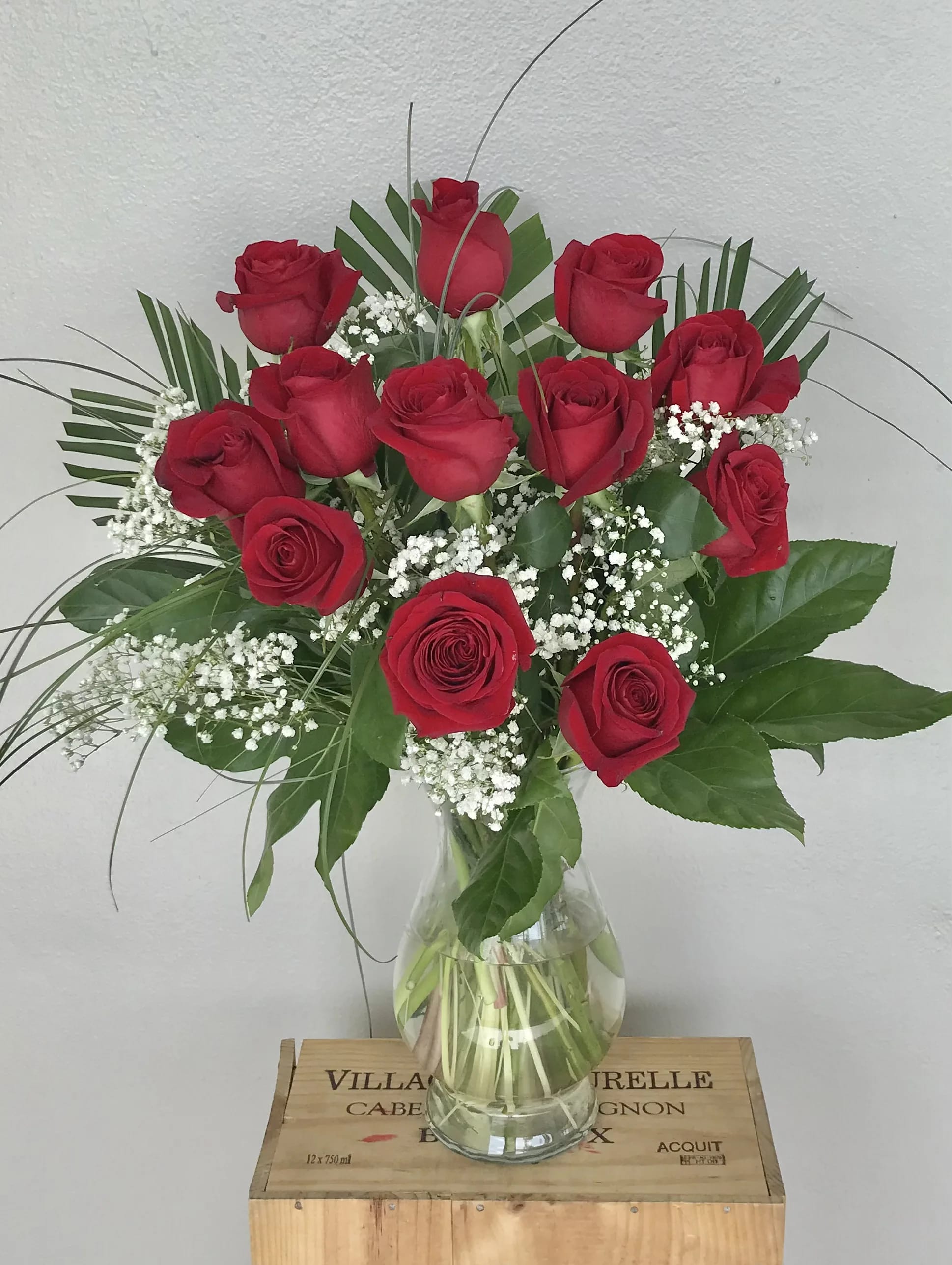 Red roses arranged in a clear glass vase with baby's breath