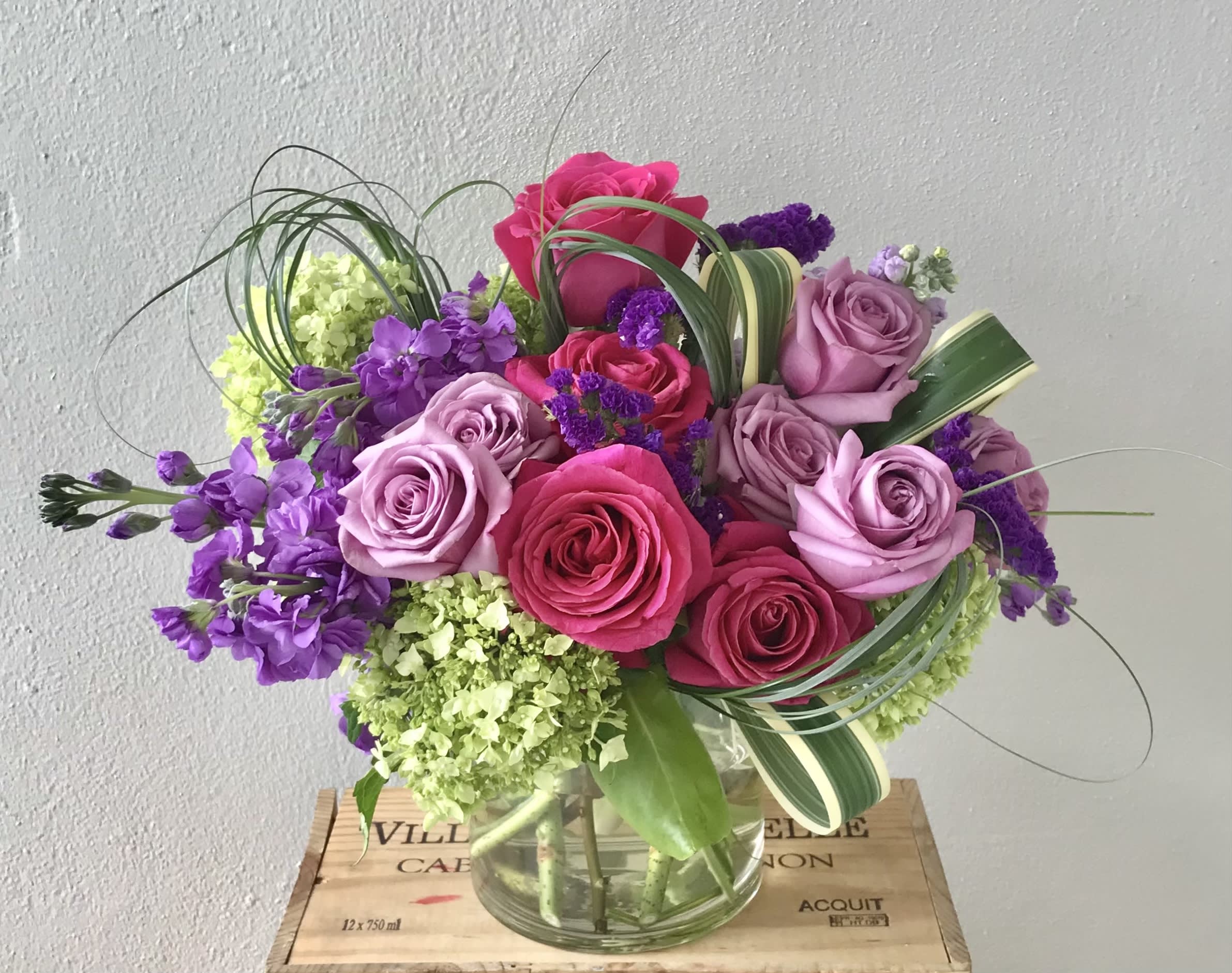 Bouquet of pink and lavender roses with purple flowers in a glass vase