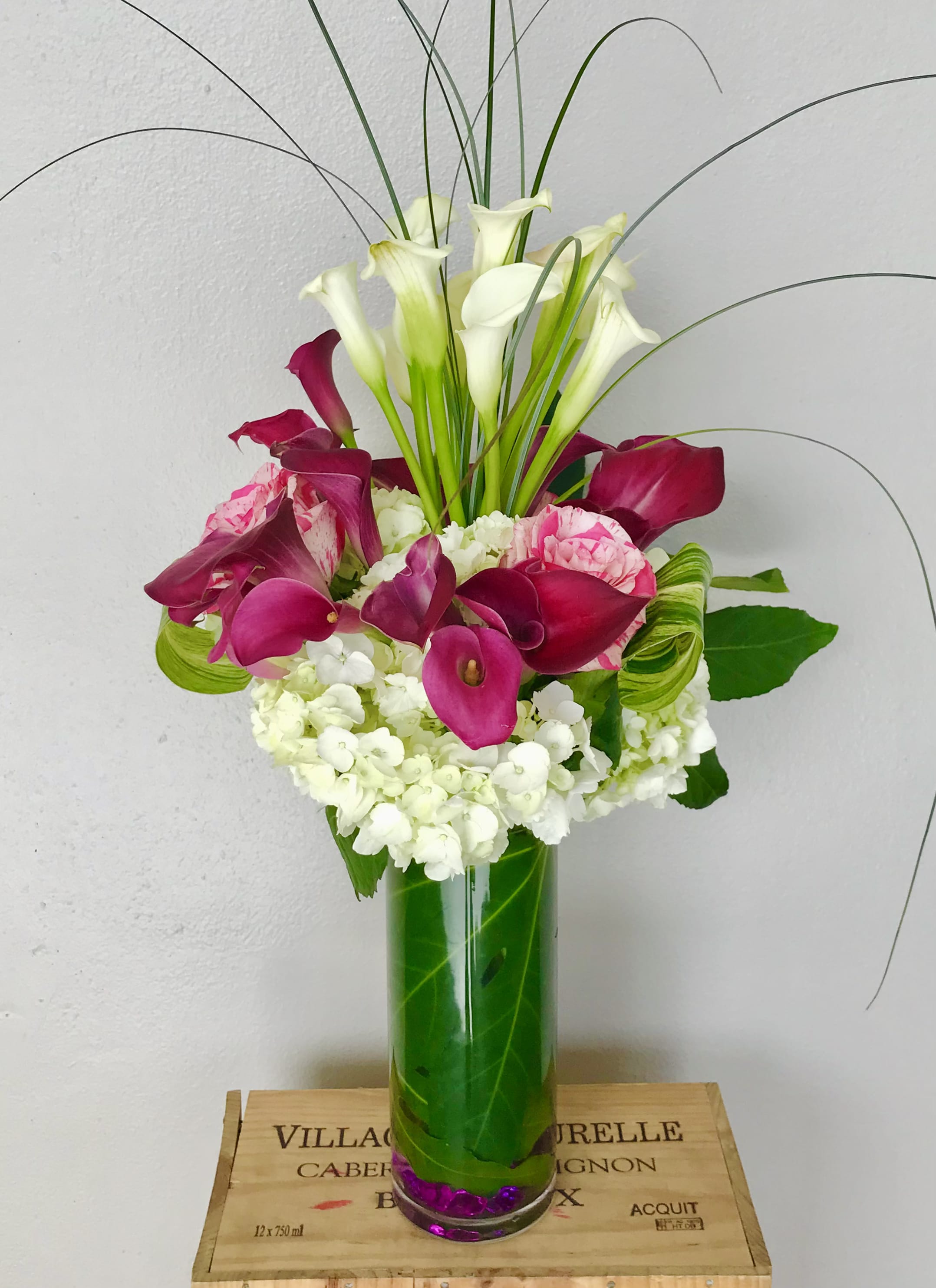 Pink and white calla lily arrangement in a tall glass vase