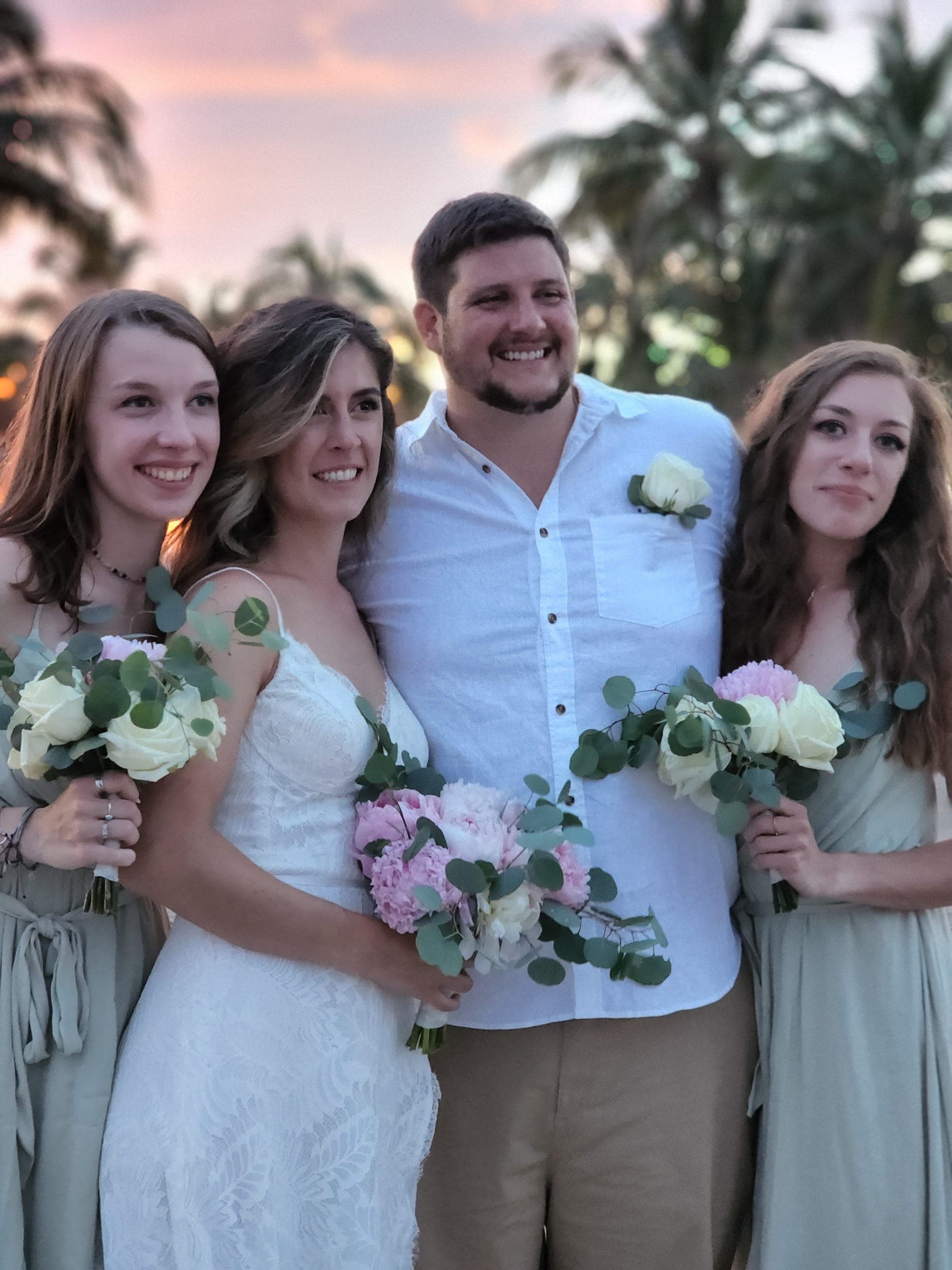 Wedding party holding white and pink bouquets at sunset