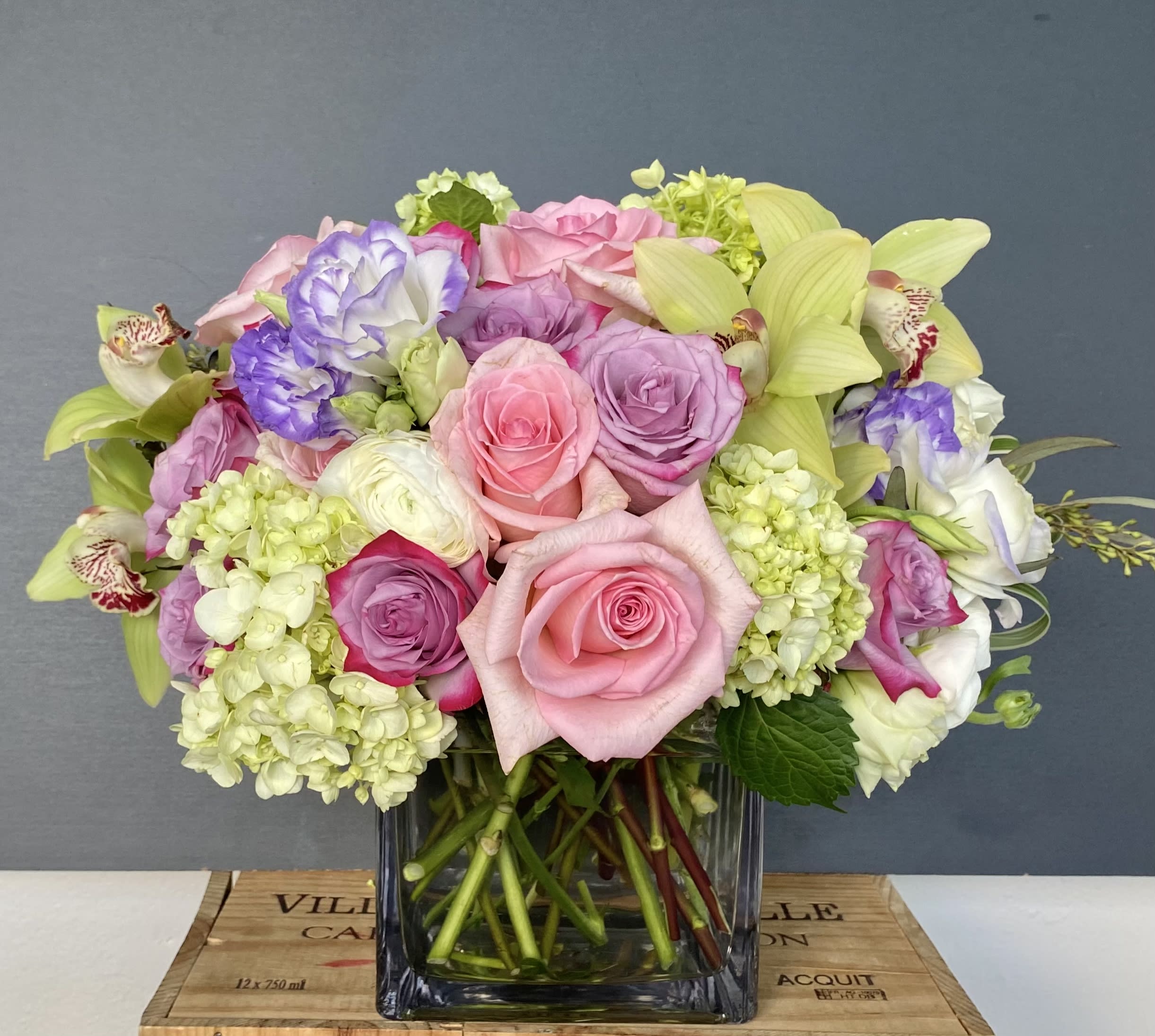 Mixed bouquet of pink and lavender roses with pale green hydrangeas in a glass vase