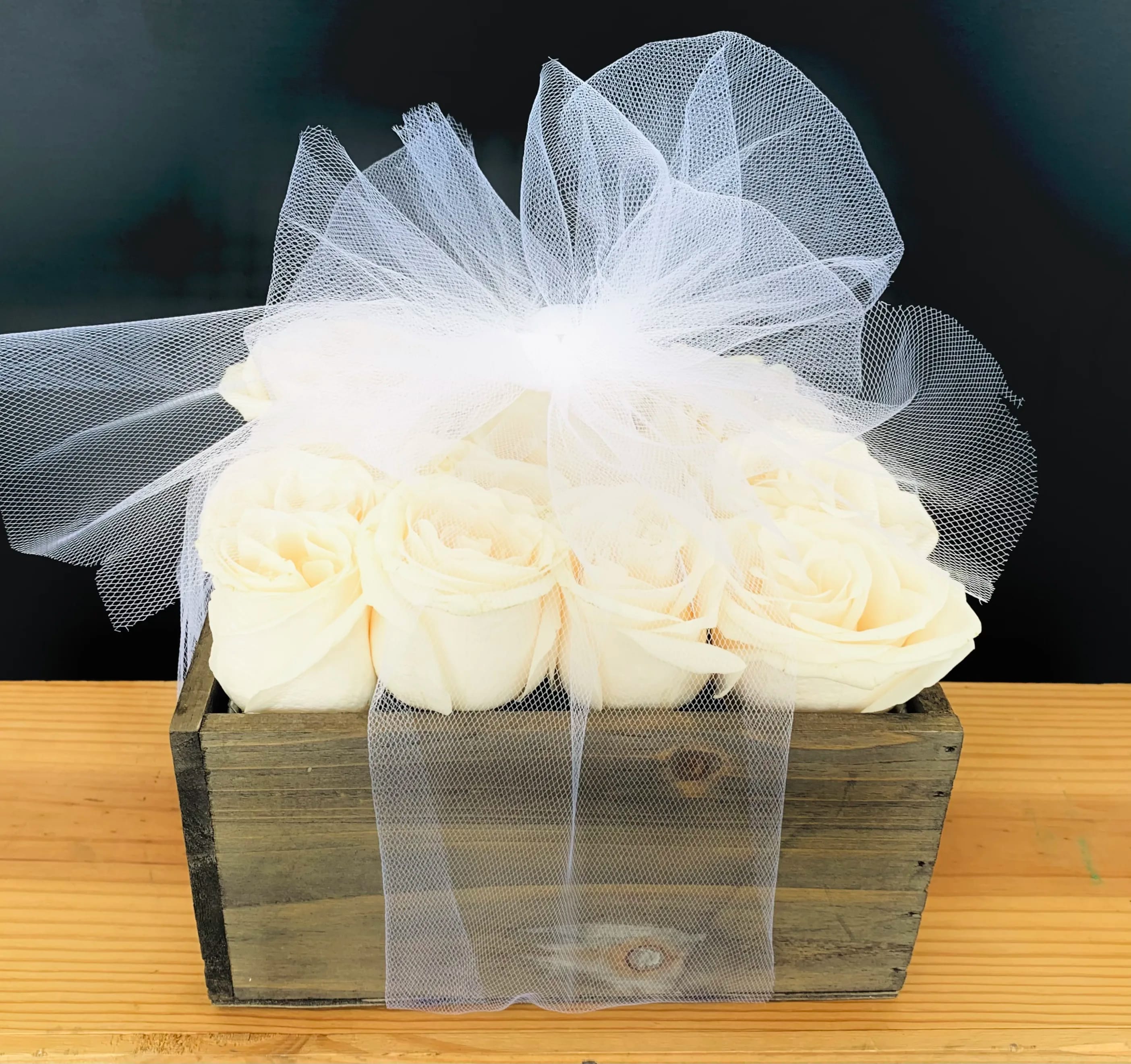 White roses in a rustic wooden box with a sheer tulle bow