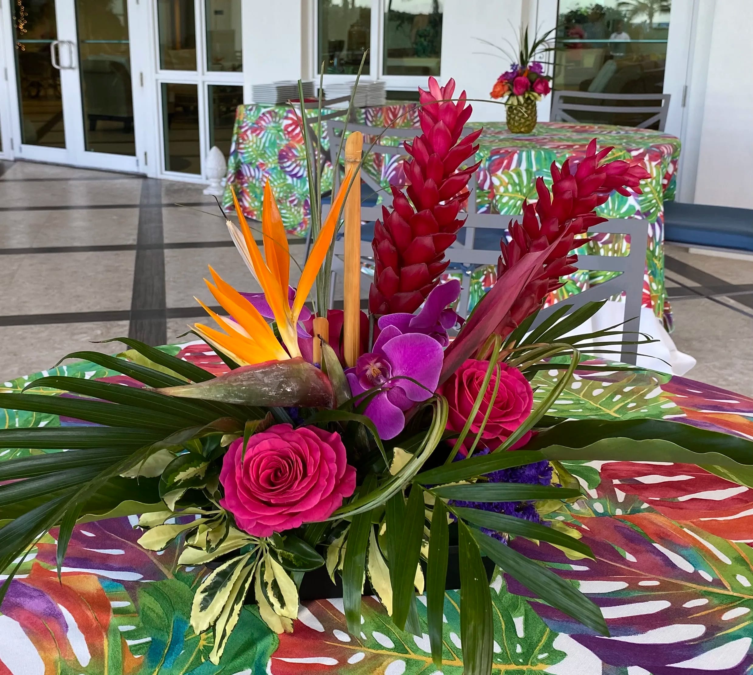 Tropical floral centerpiece with pink roses, purple orchids, and red ginger flowers
